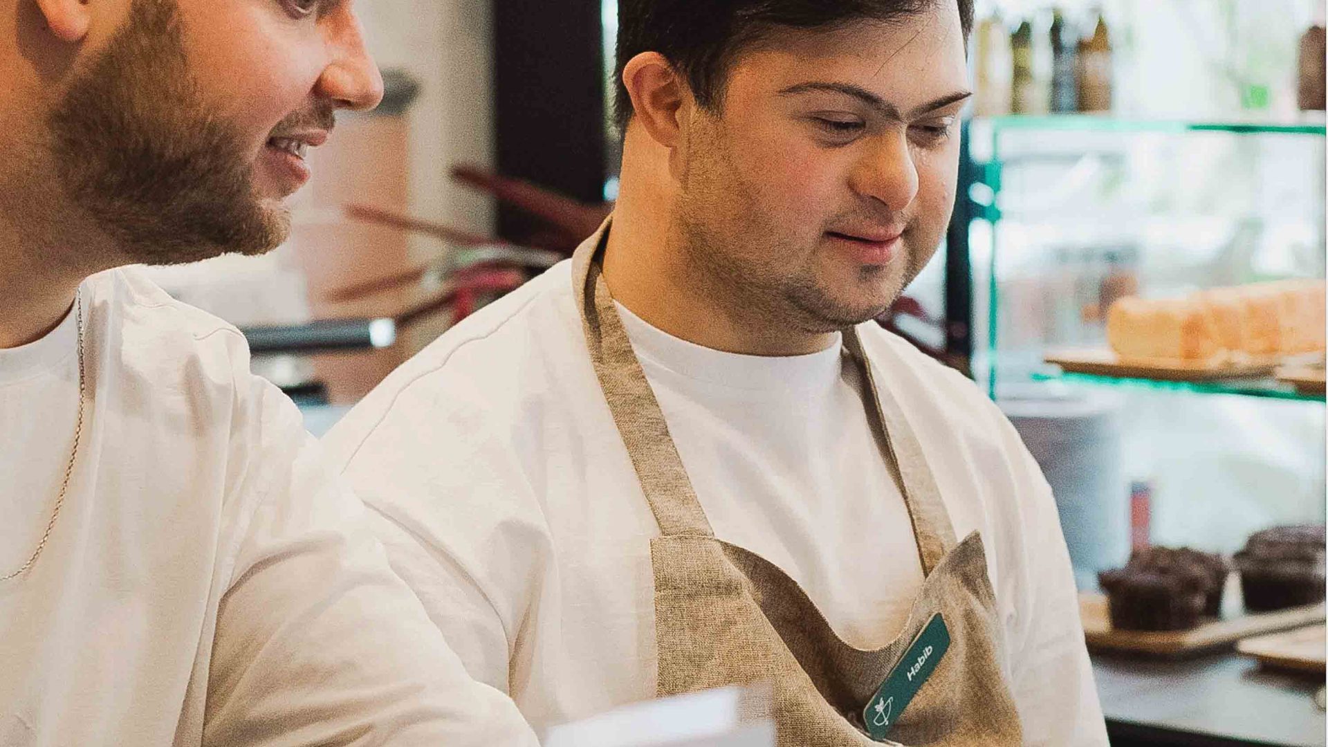 Two men work in a cafe kitchen.