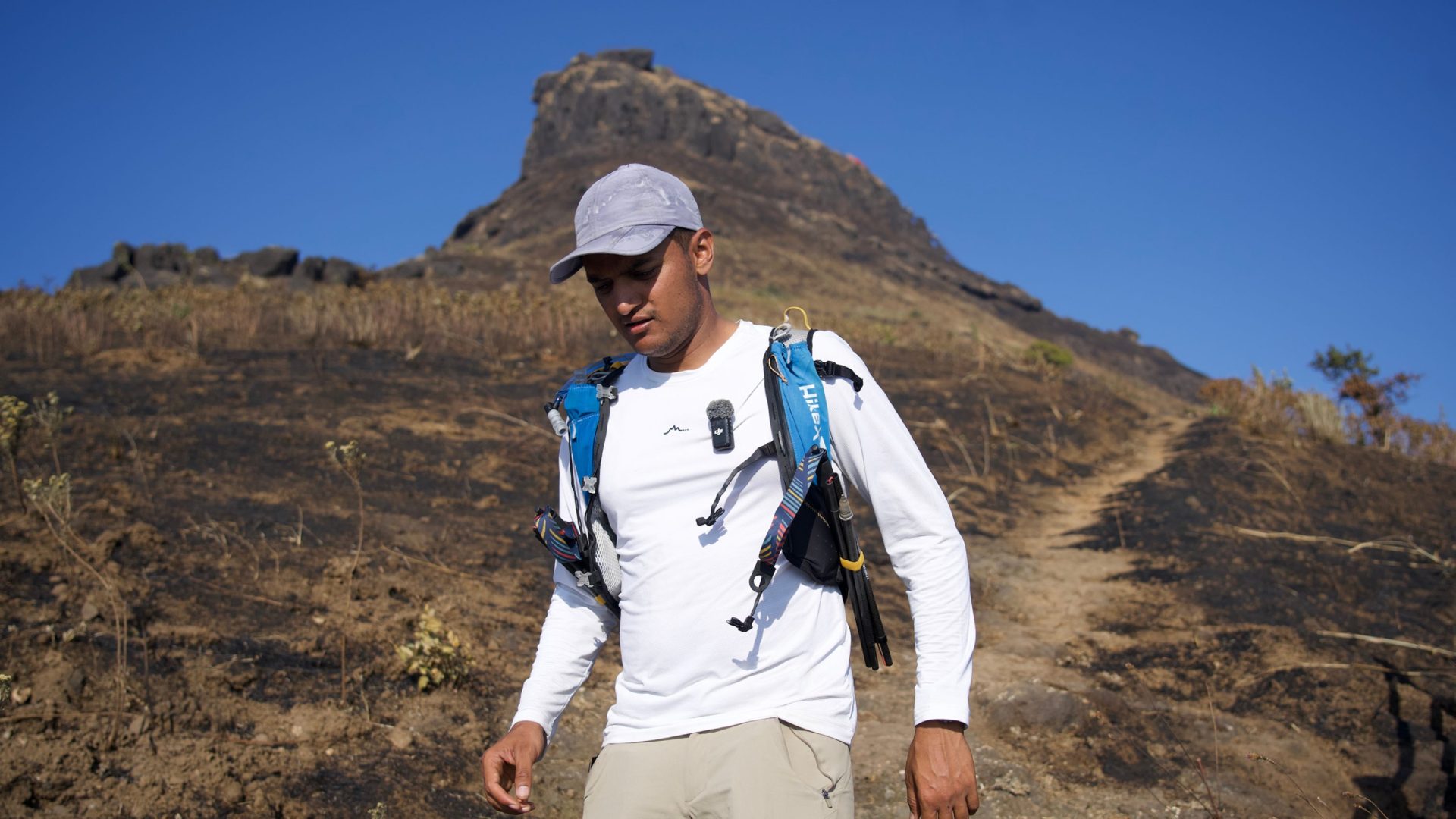 Man in white walks down mountain landscape.