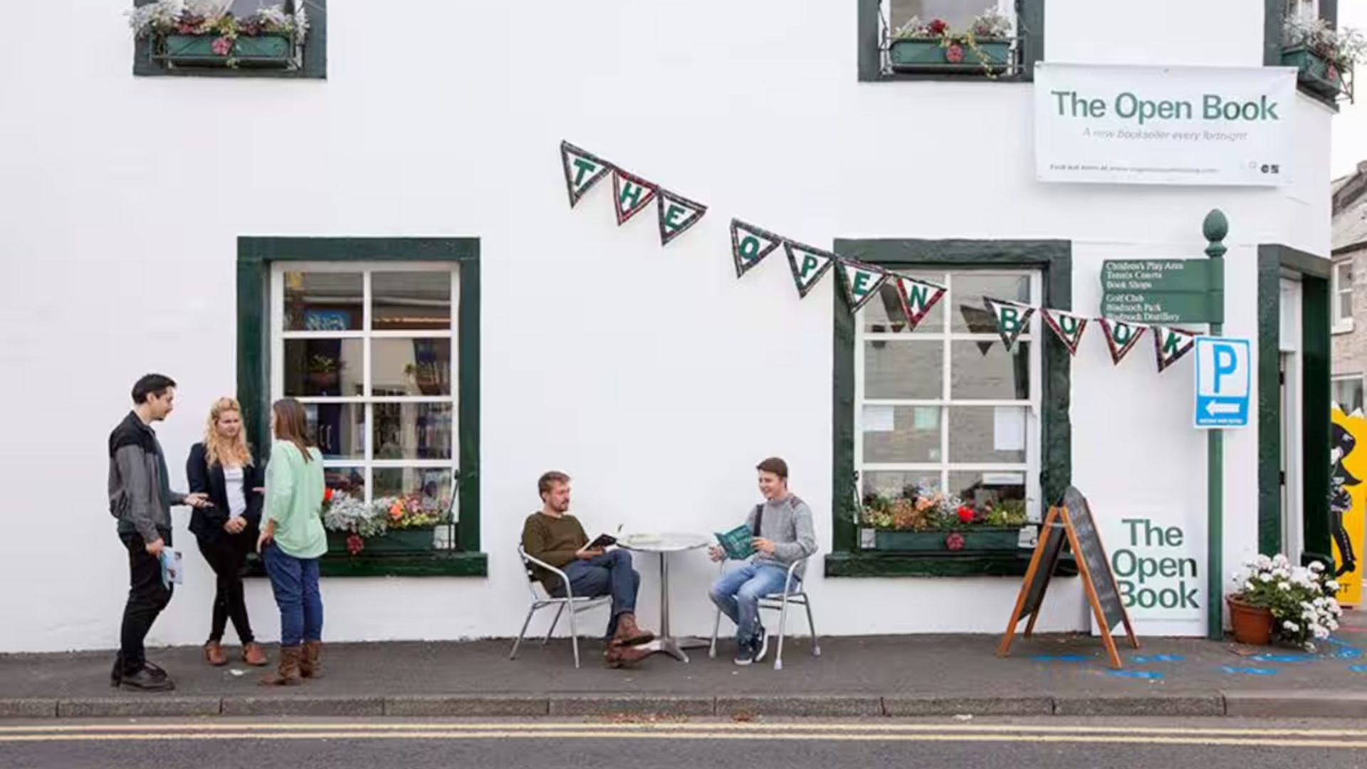 People gather outside bookshop under bunting.