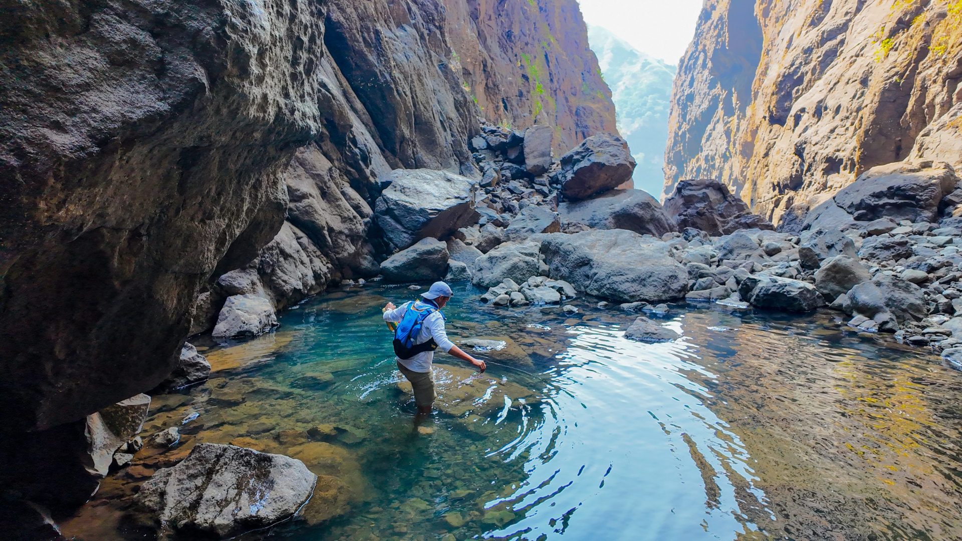 Man wades through green pool of water.