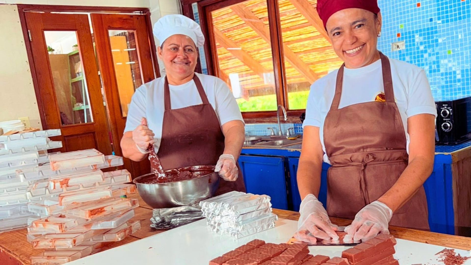 Two smiling women wearing red chef hats.