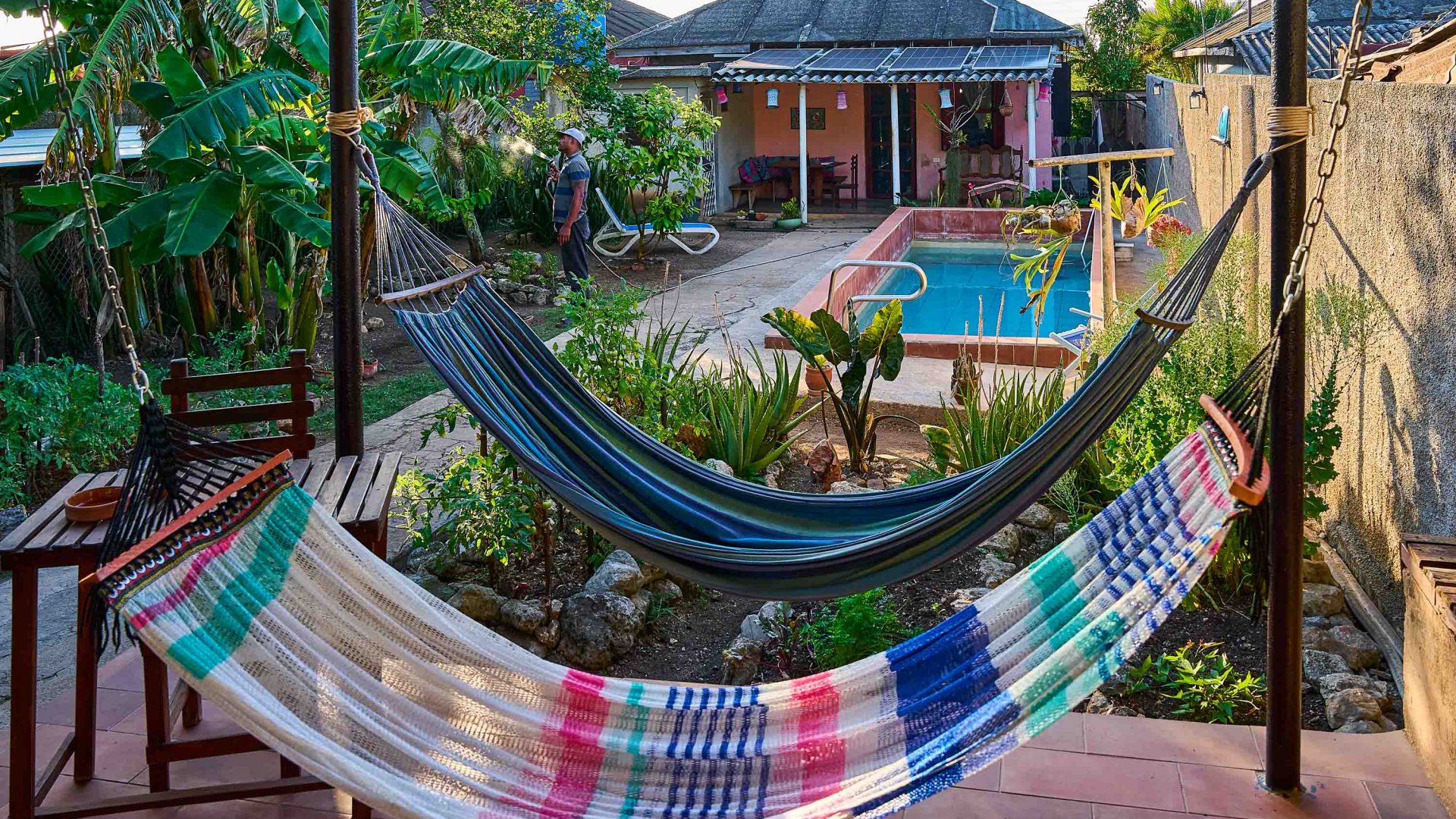 A house with a pool and two hammocks in the garden.