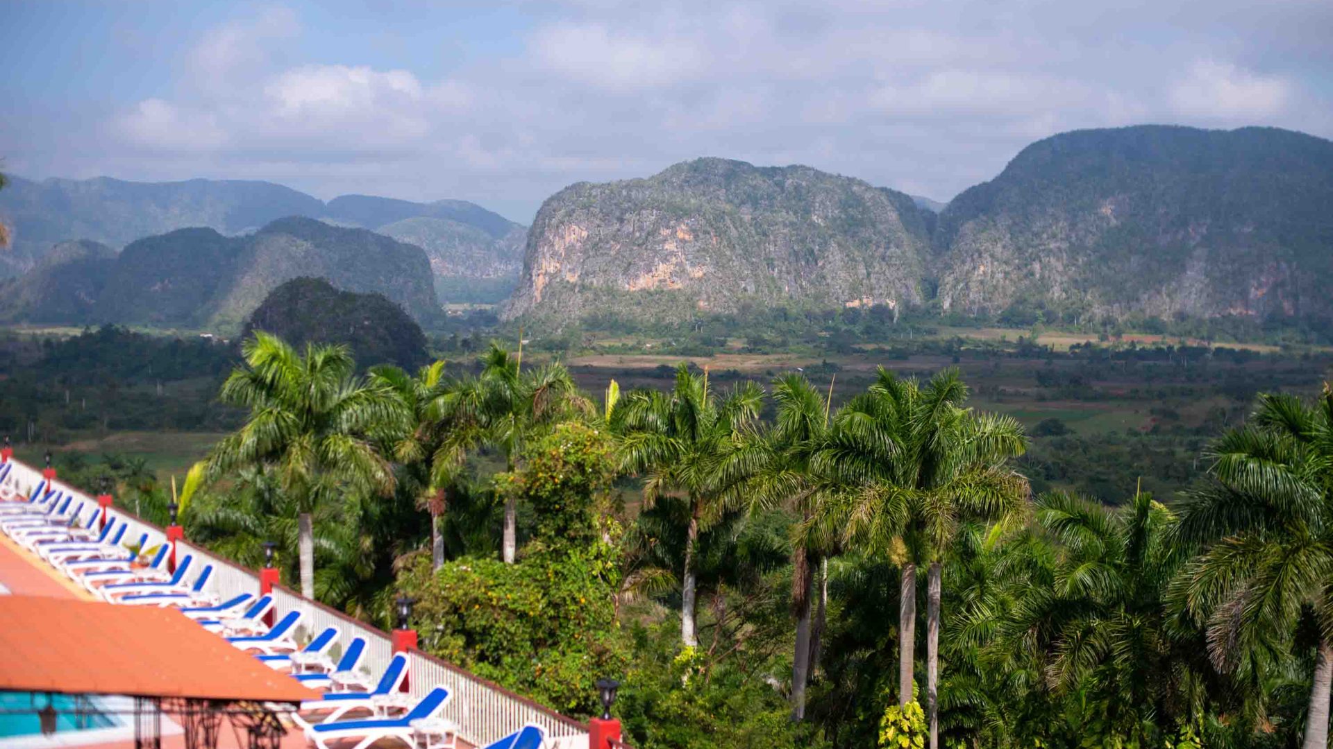 Empty deckchairs look out at lush green mountains.