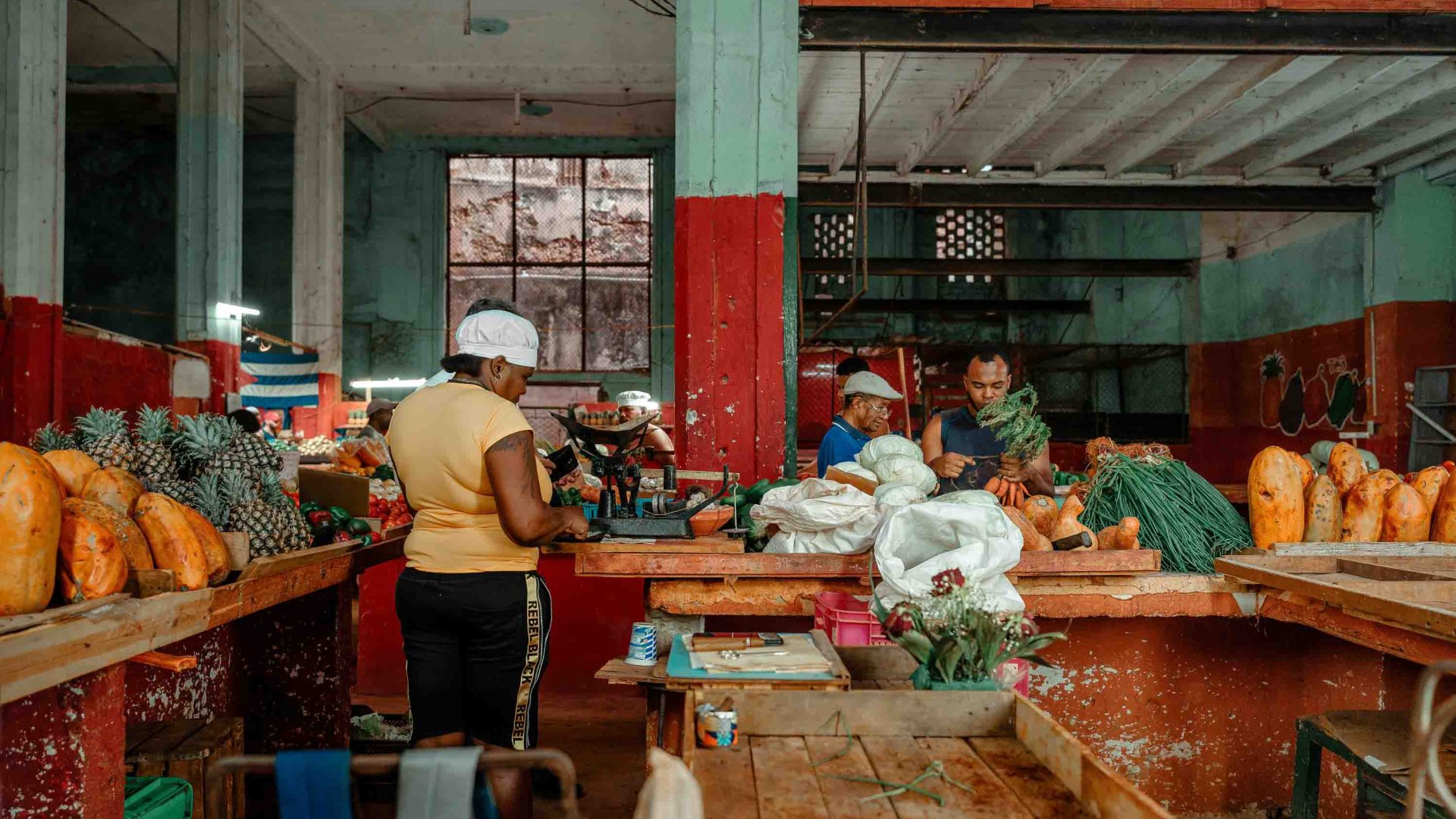 A woman sells pineapples and other produce at a market.