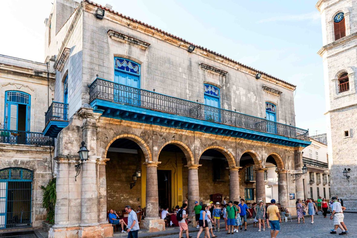 Tourists in a square under the arches of a building.