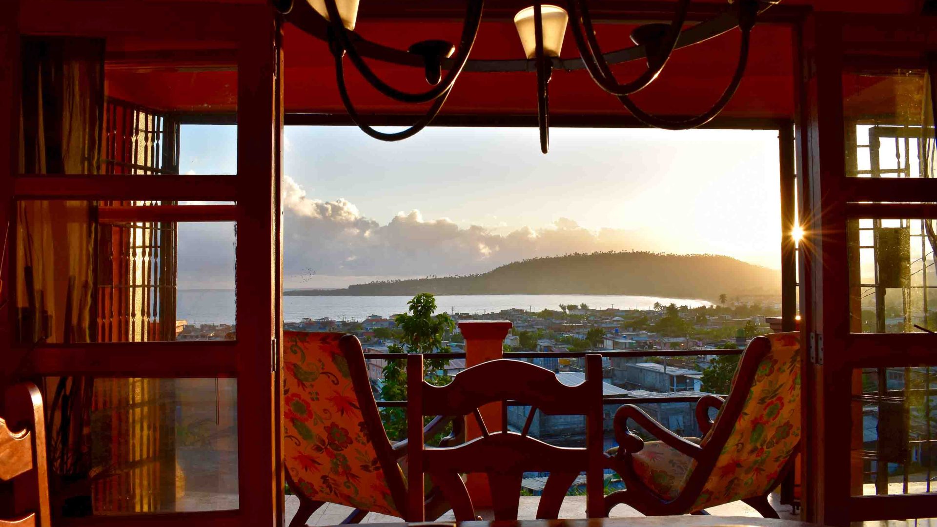 Seats on a patio overlook the water as the sun comes softly through the window.