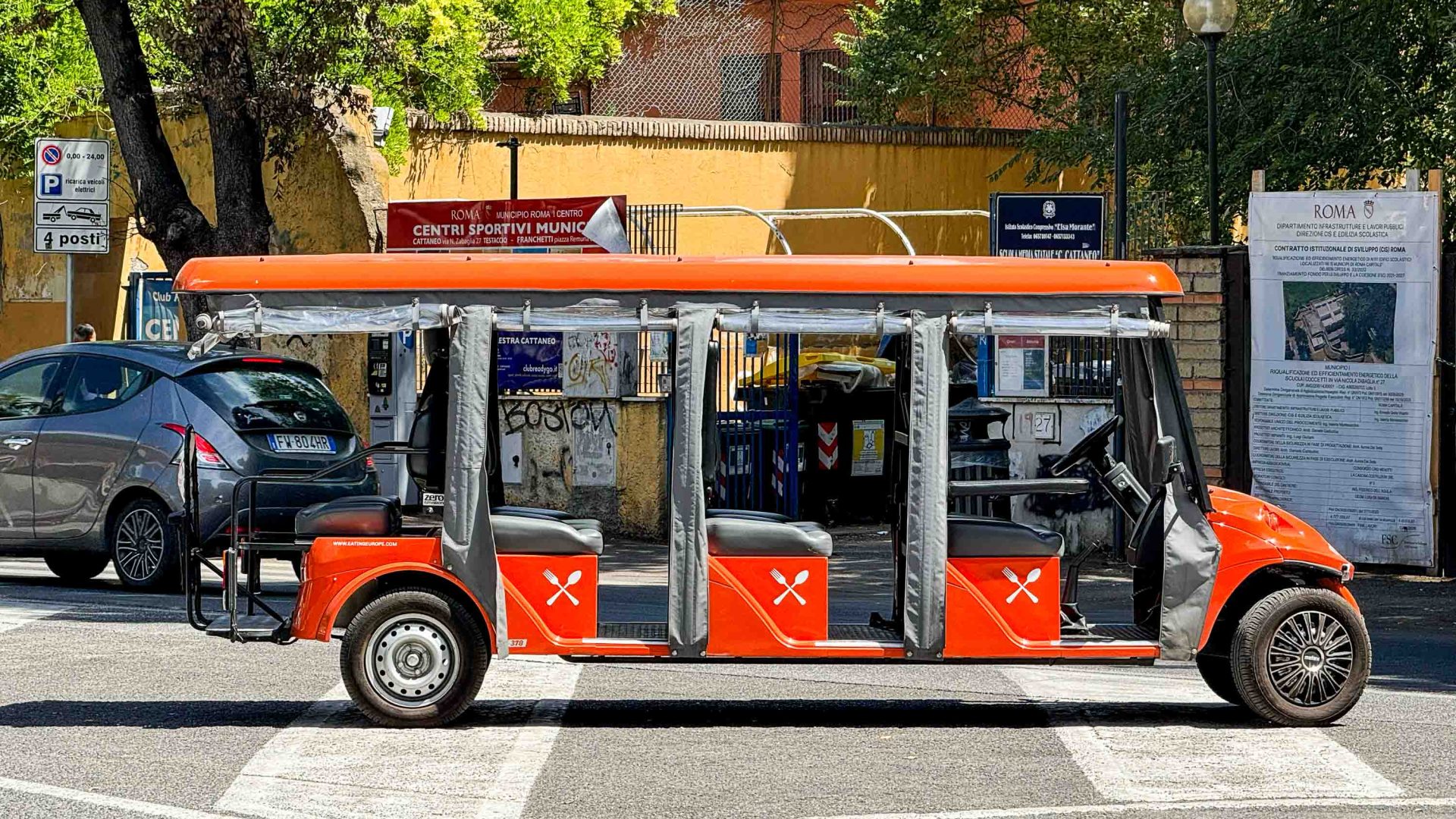 A red electric vehicle with multiple seats in the street.