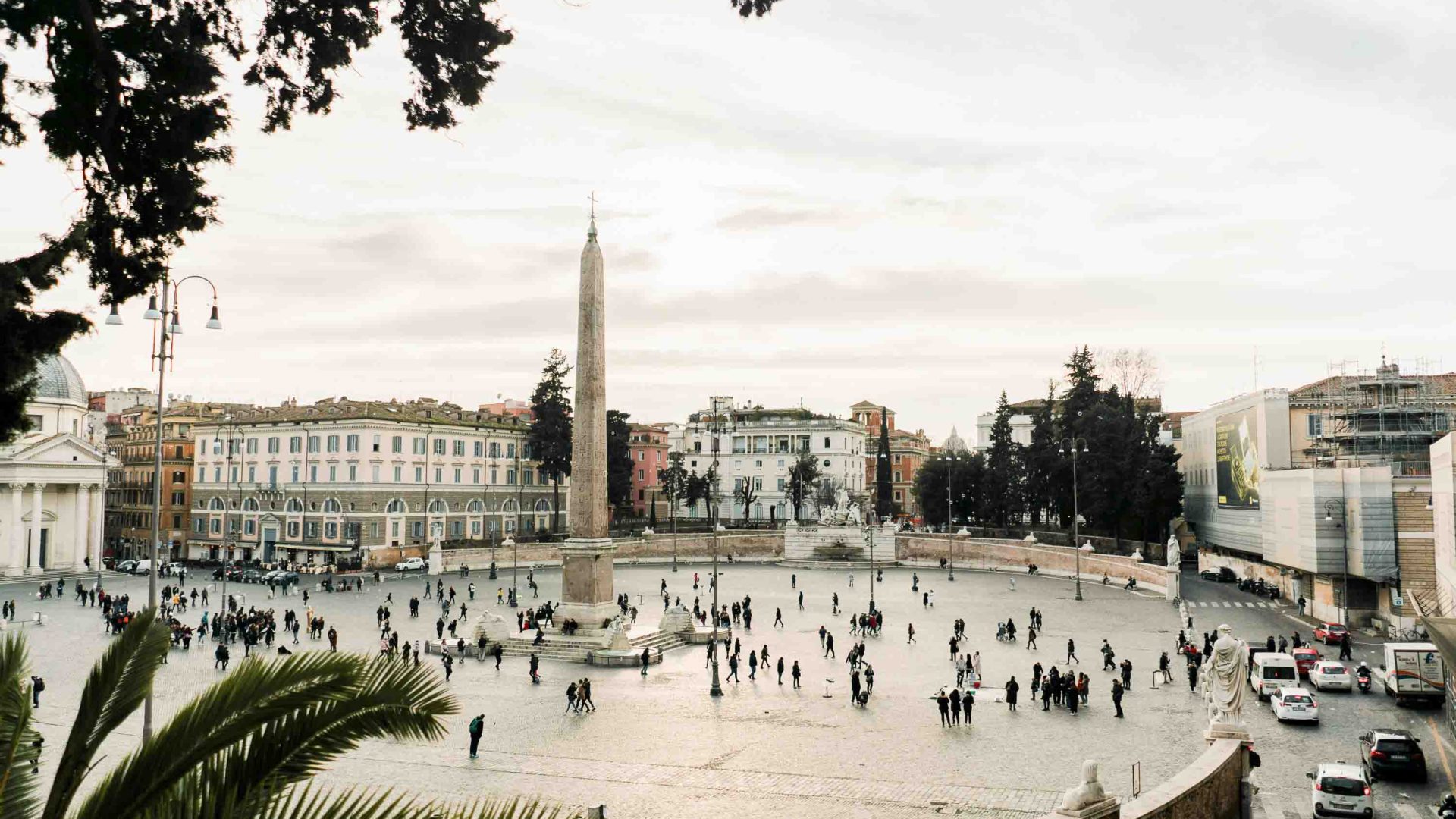 Looking down over a plaza with people in it that is surrounded by buildings and a church.