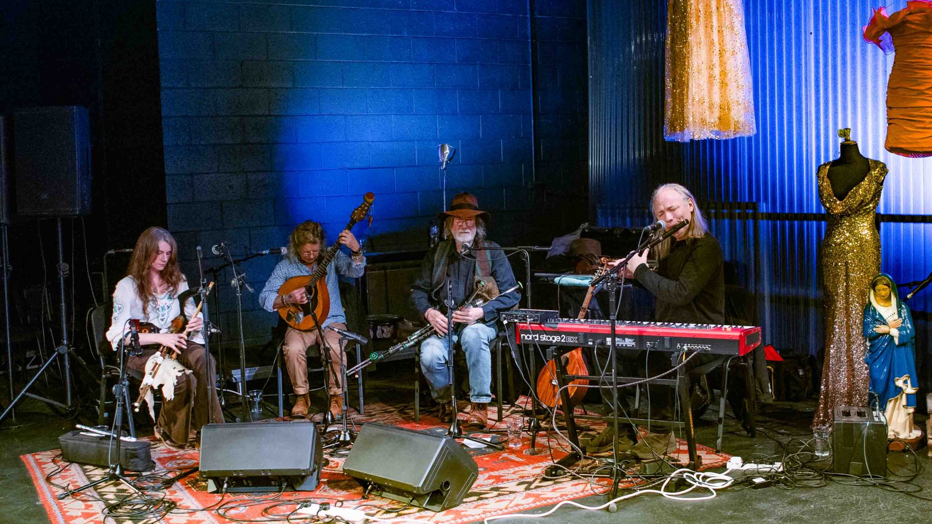 A group of musicians performs against a blue lit up wall.