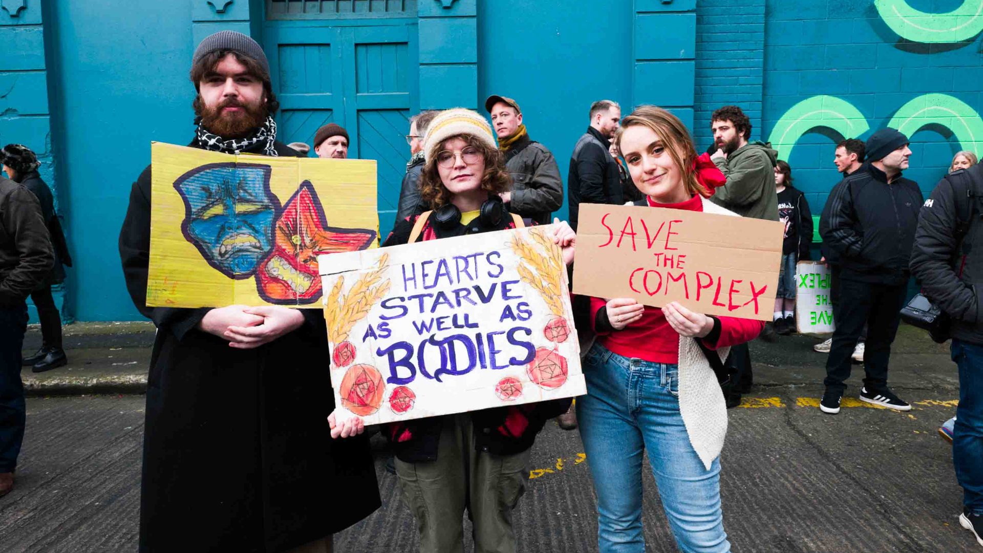 A group of protestors hold signs. One reads "Hearts starve as well as bodies".