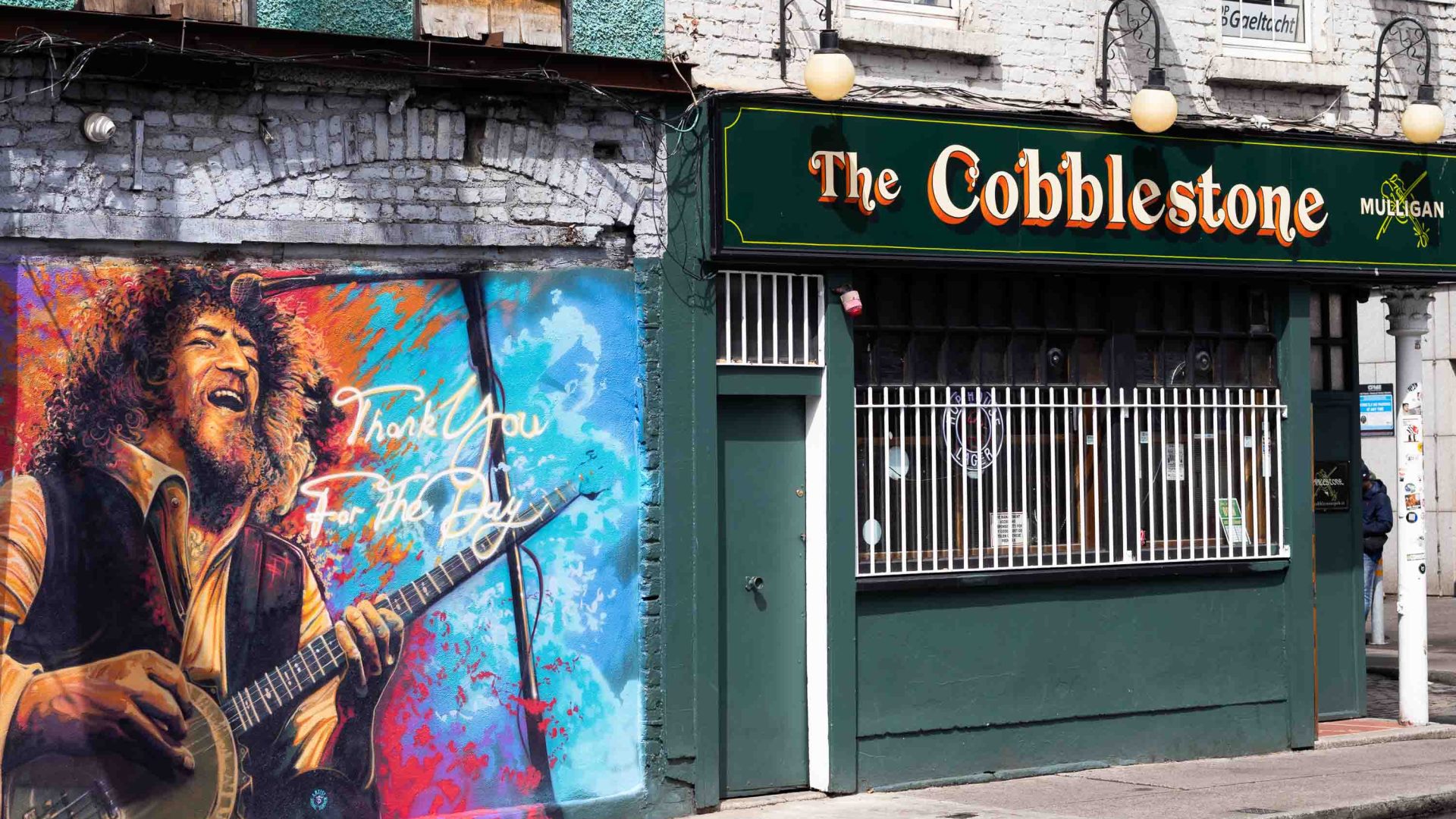 A mural on the wall of a venue with the name "The Cobblestone" painted on the outside.