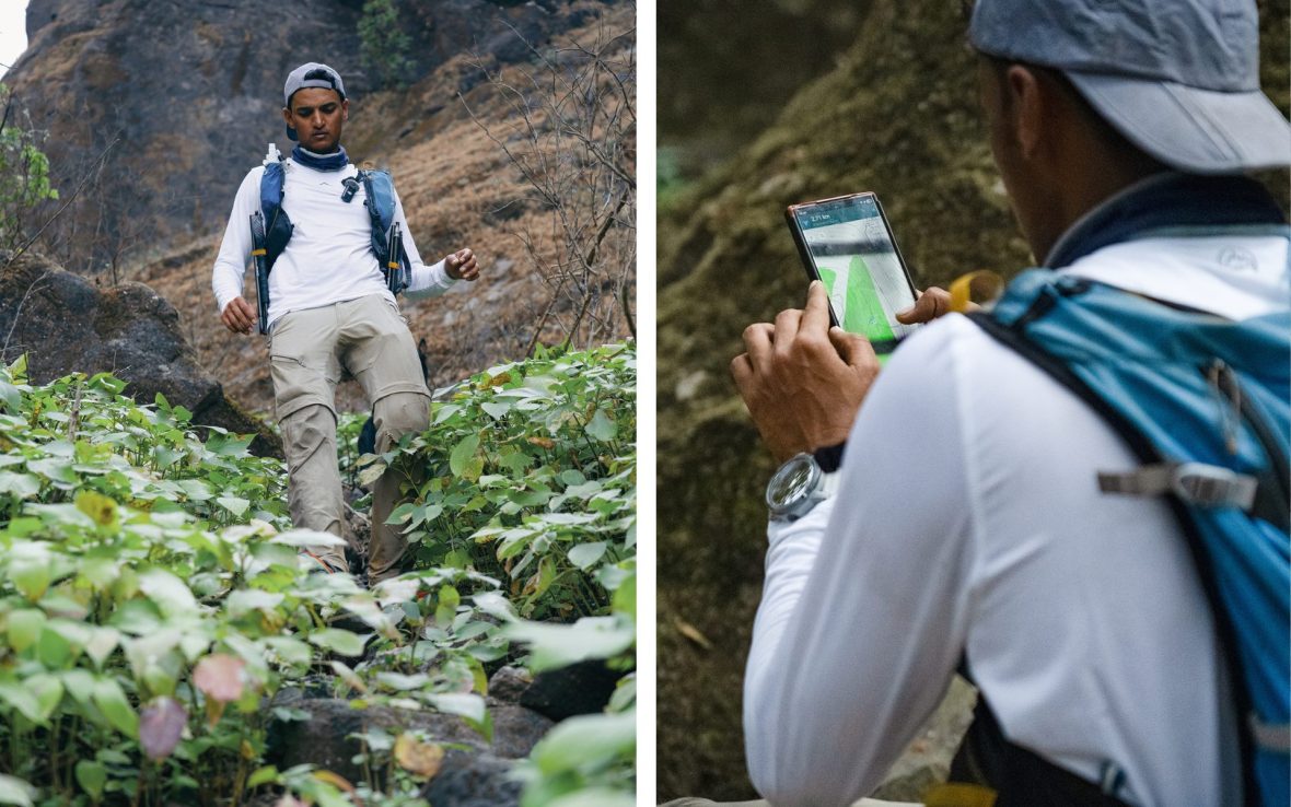 Man in white shirt hikes down green trail using phone map