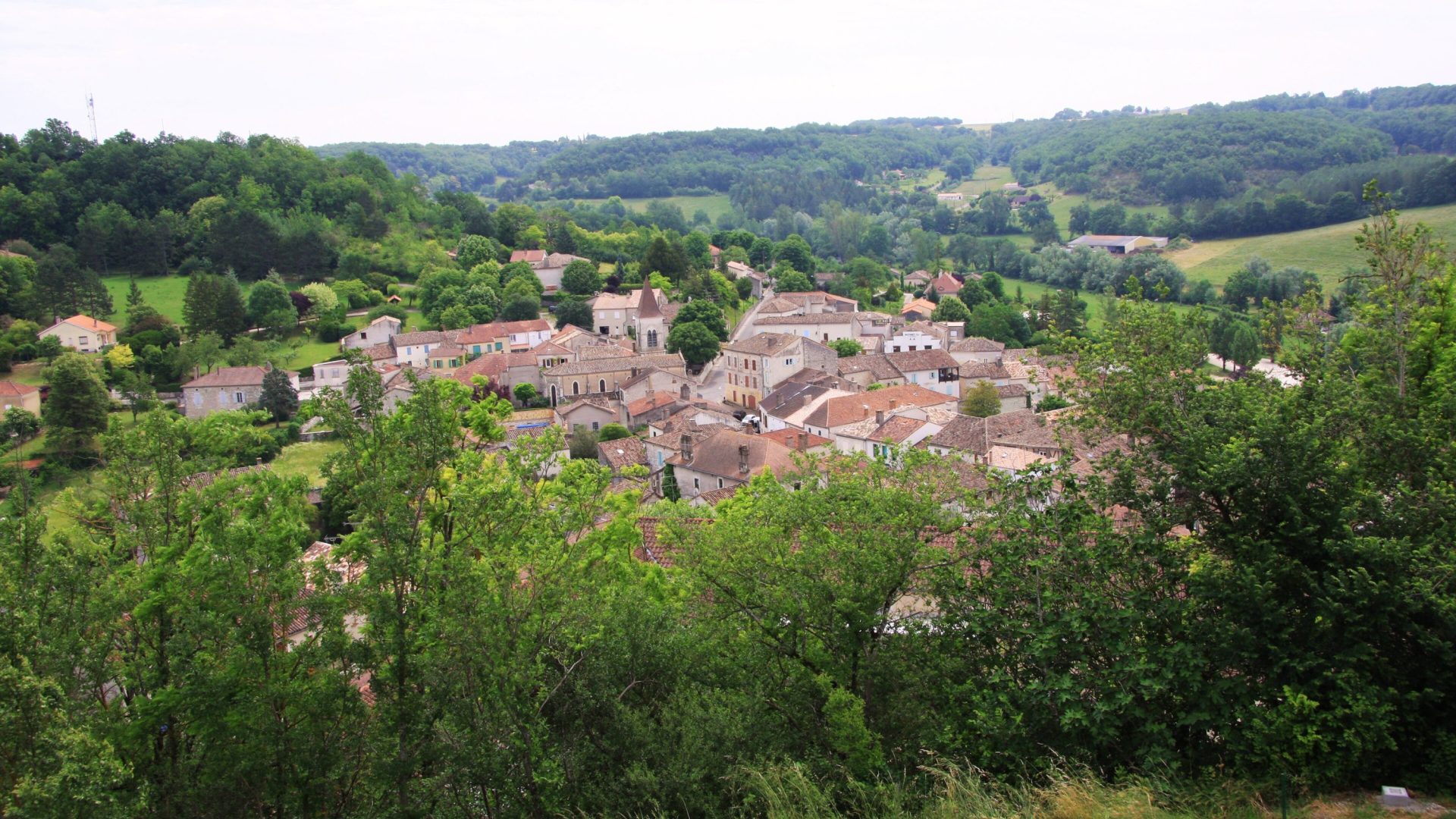 Brown roof tops nestled in green valley.