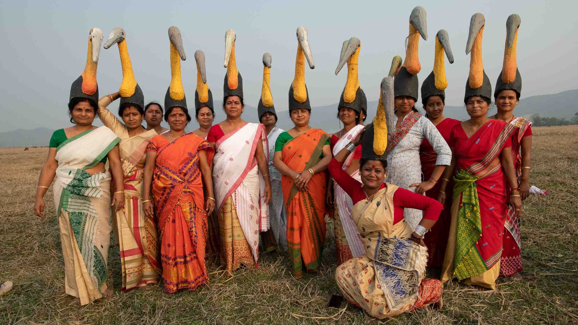 An army of women wearing headwear that looks like storks while in their traditional Indian saris.