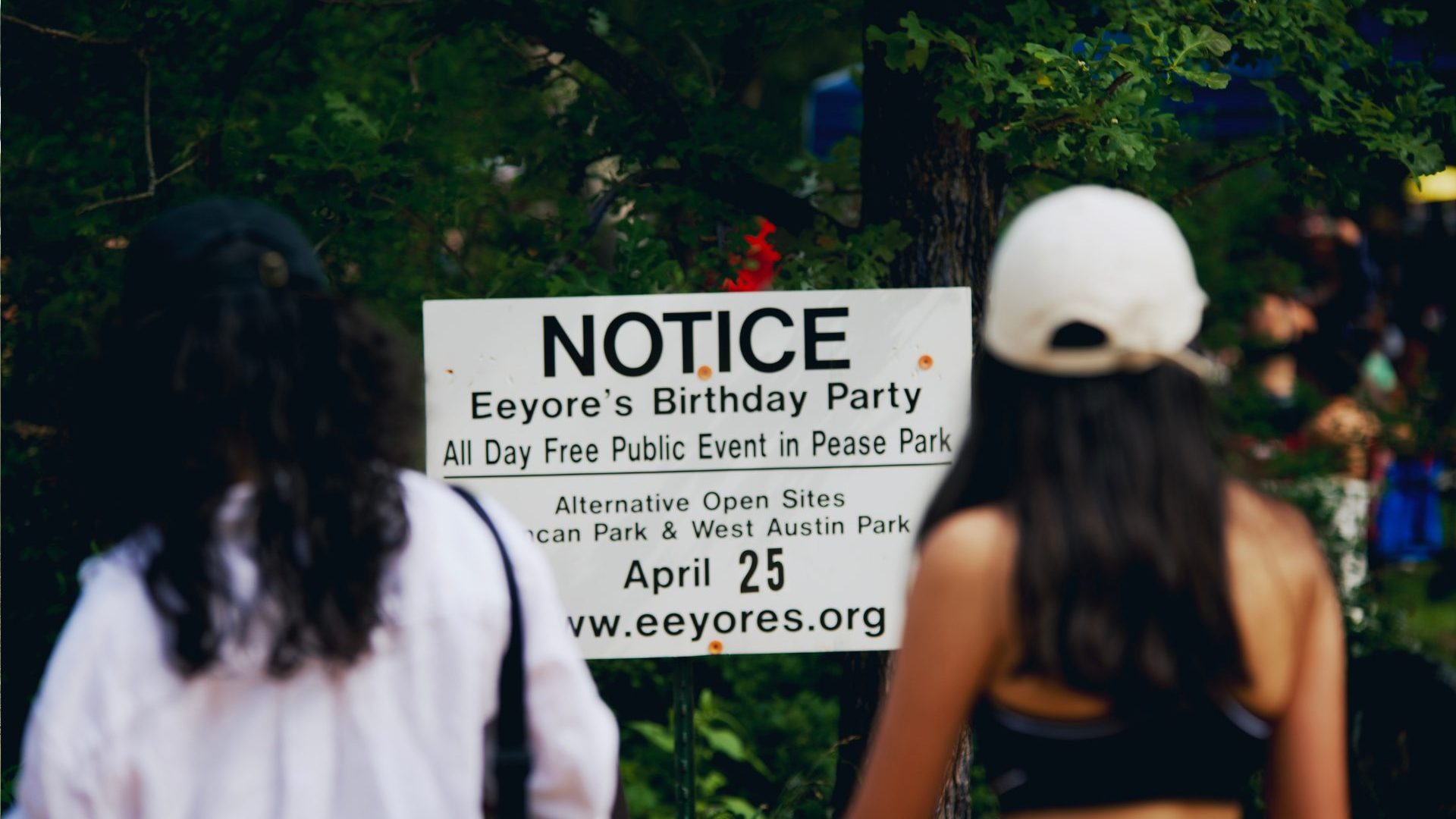 Sign reading: NOTICE Eeyore's Birthday Party free public event at Pease Park.