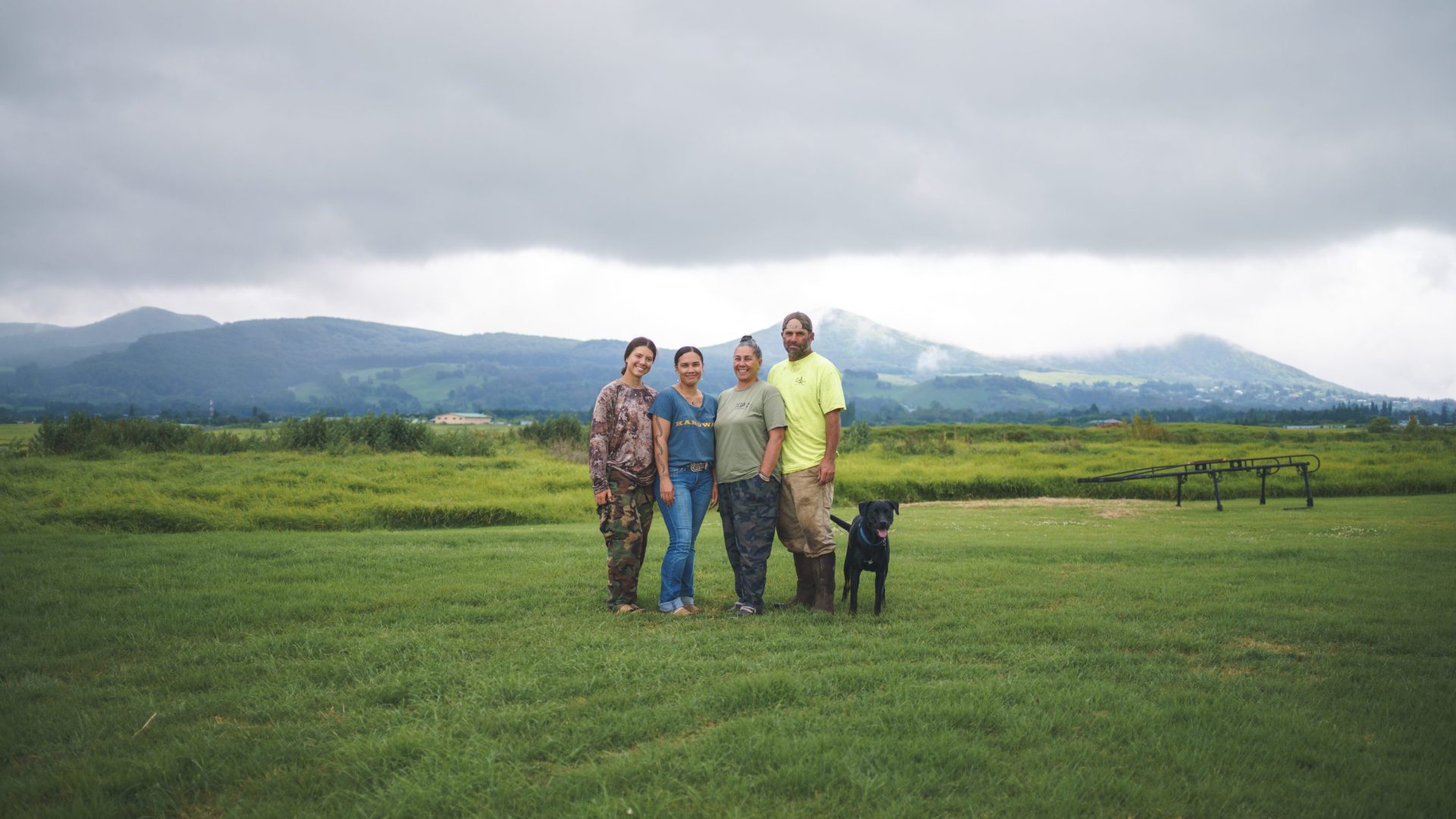 Three women, one man and a dog pose for family photo.