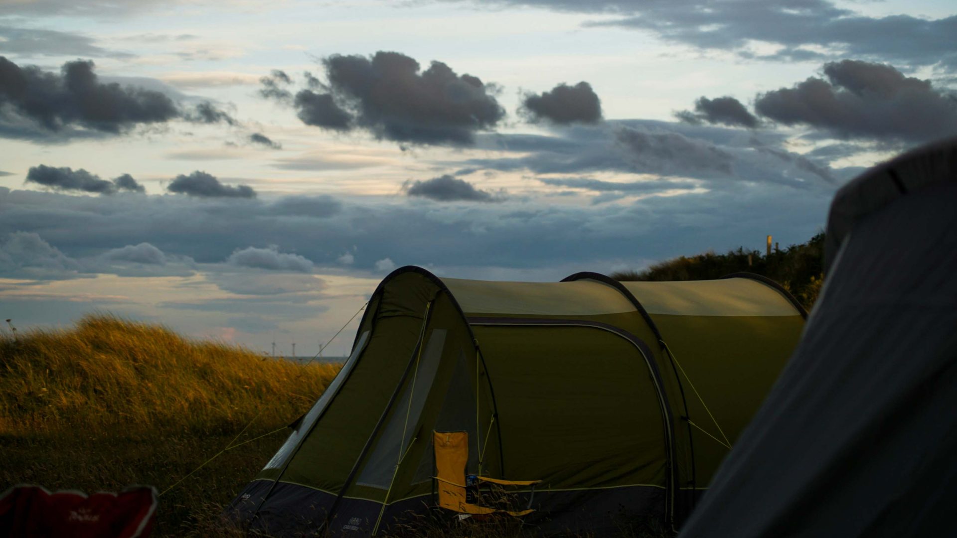 A tent pitched in a field under moody gray clouds.