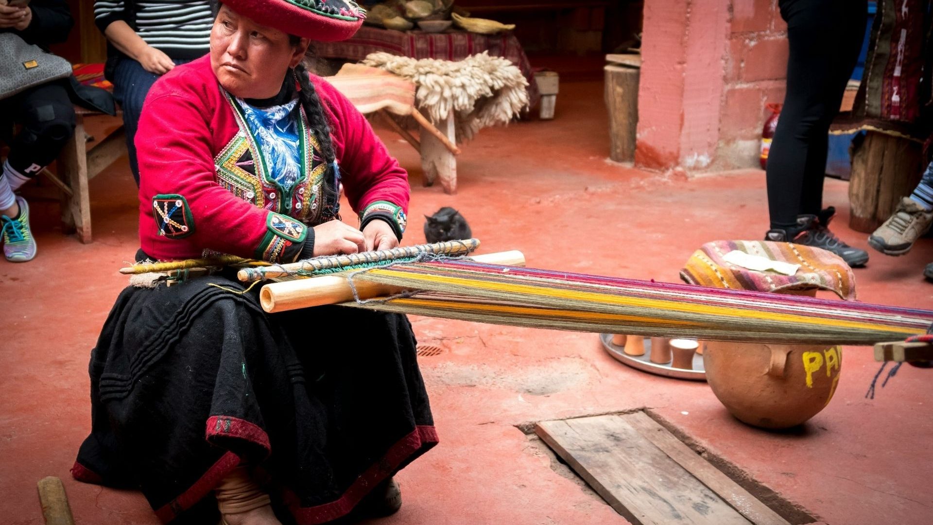 A woman in traditional clothing demonstrates how to weave