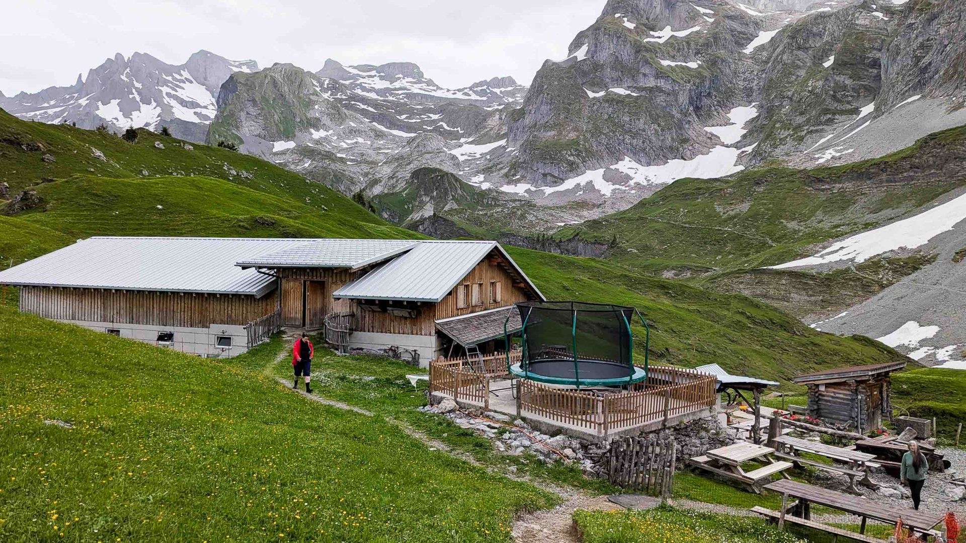 A building in a green valley backed by mountains.