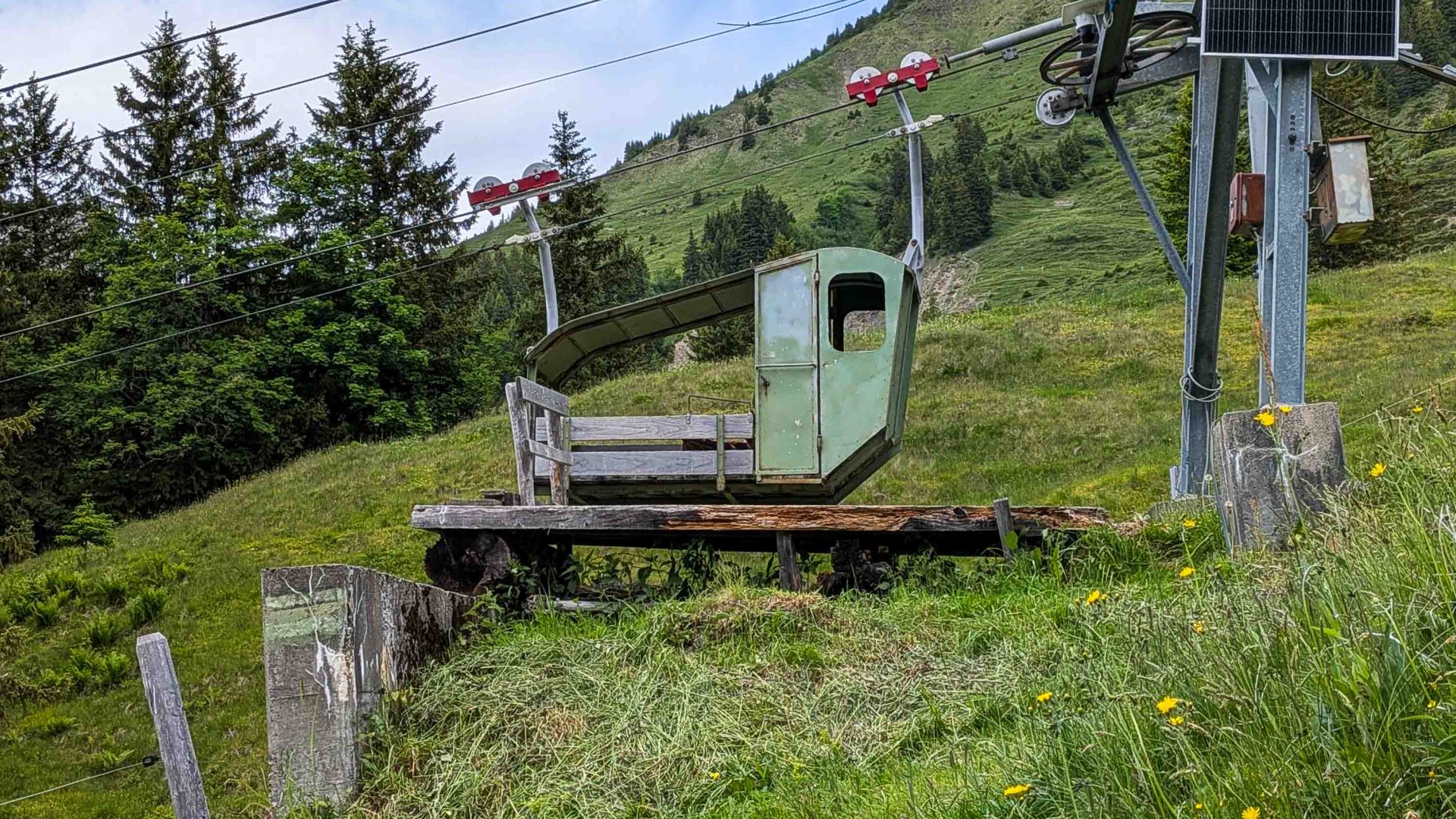 An old green and wood cable car on a platform.