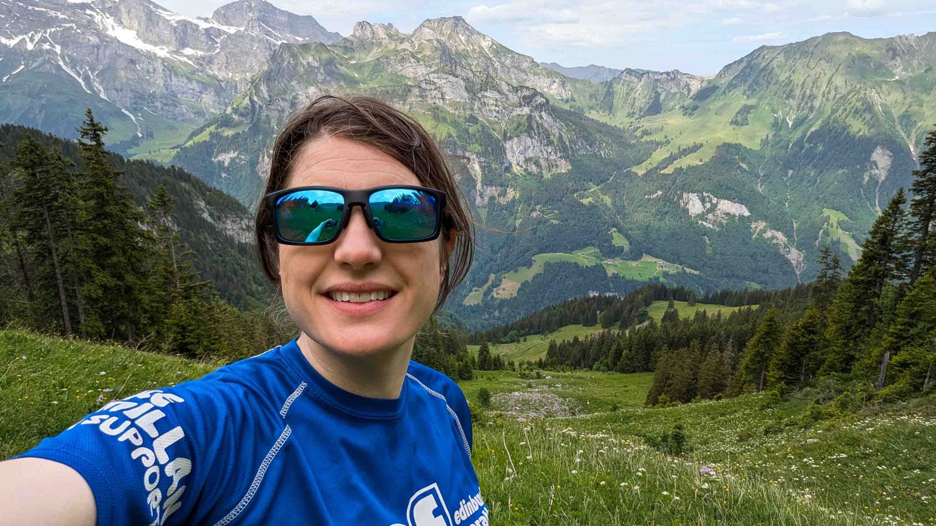 A selfie of a woman with a backdrop of mountains.