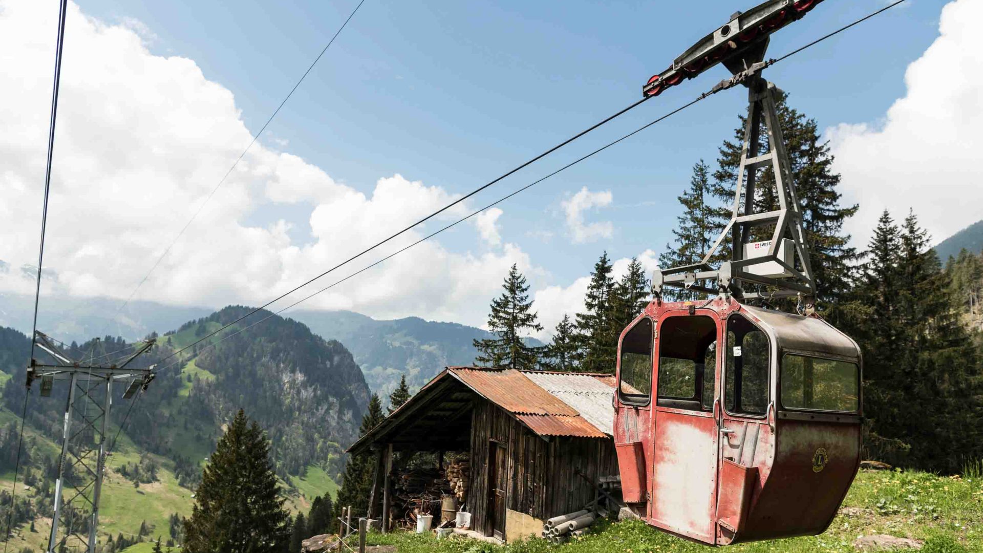 A red cable car sits ready to go down a hill.