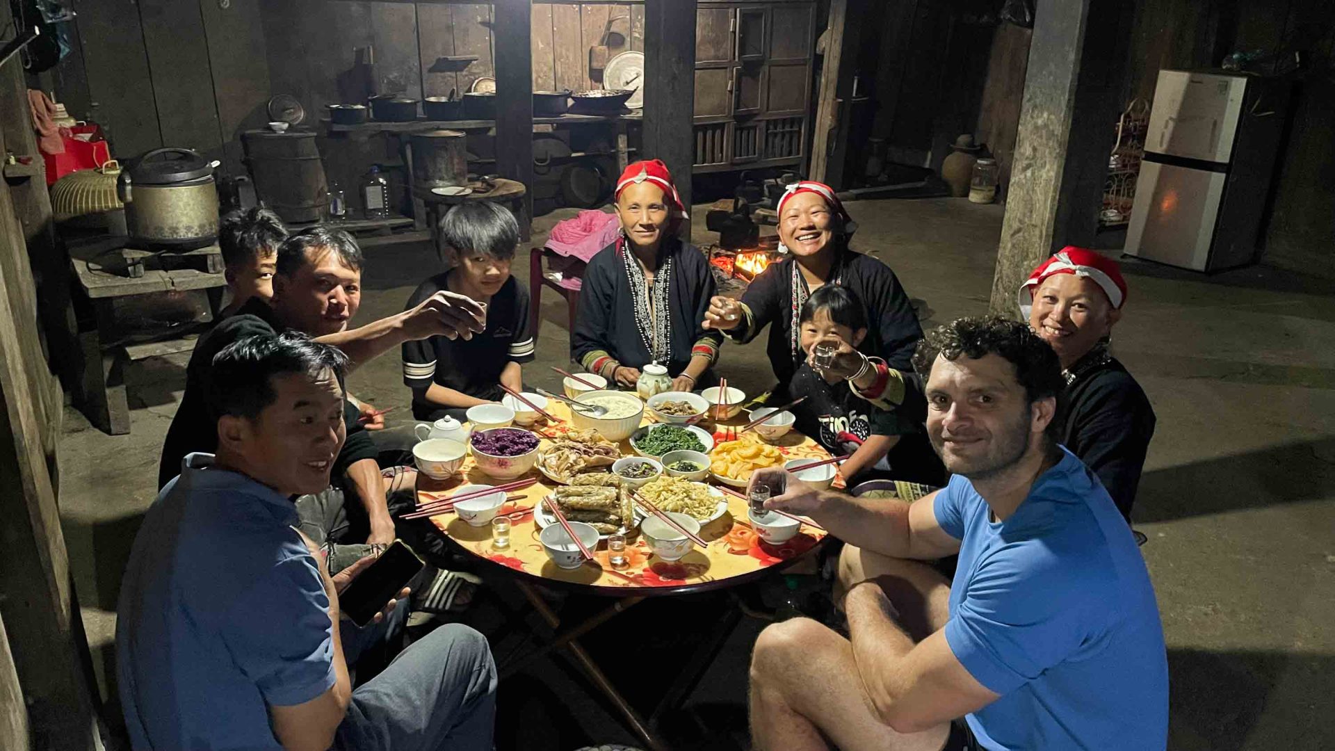 A group of people sit at a table with lots of food on it.
