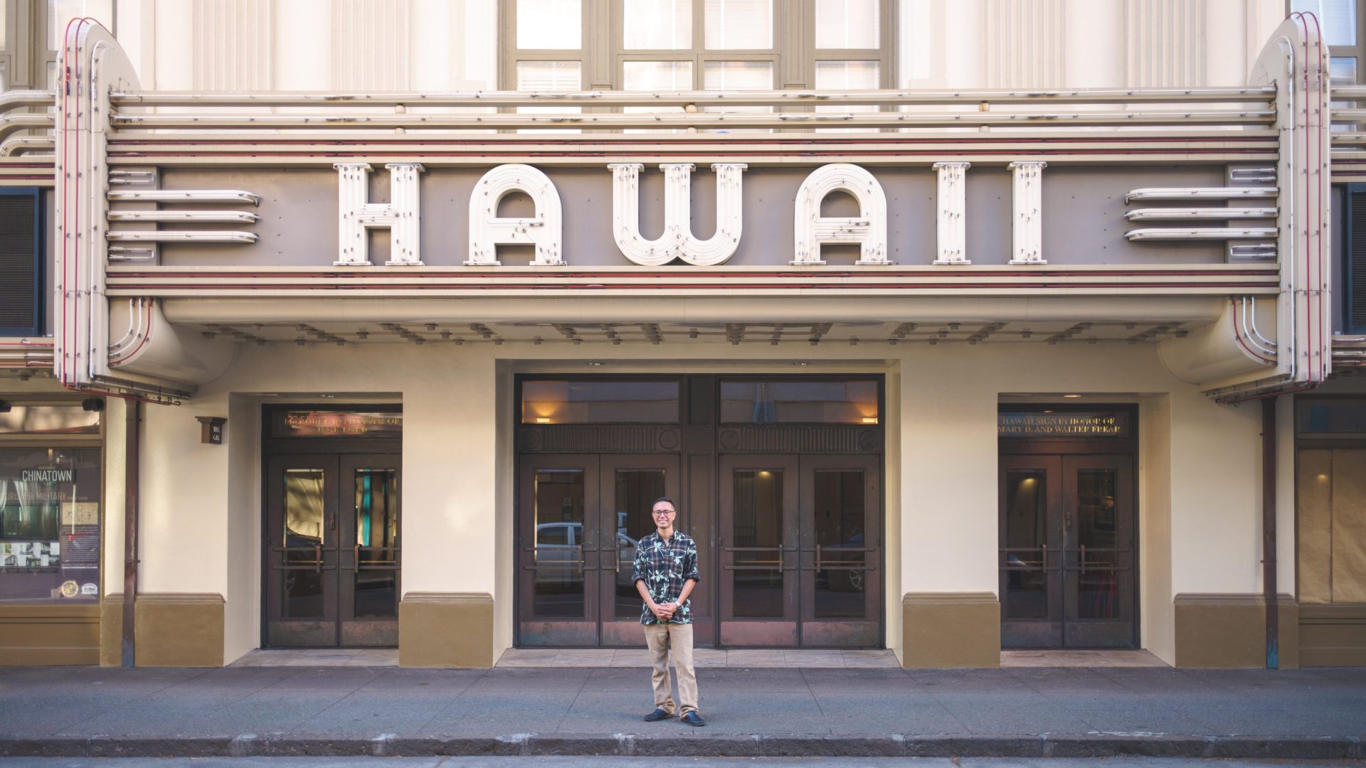 Man stands beneath theater sign reading 'Hawaii'
