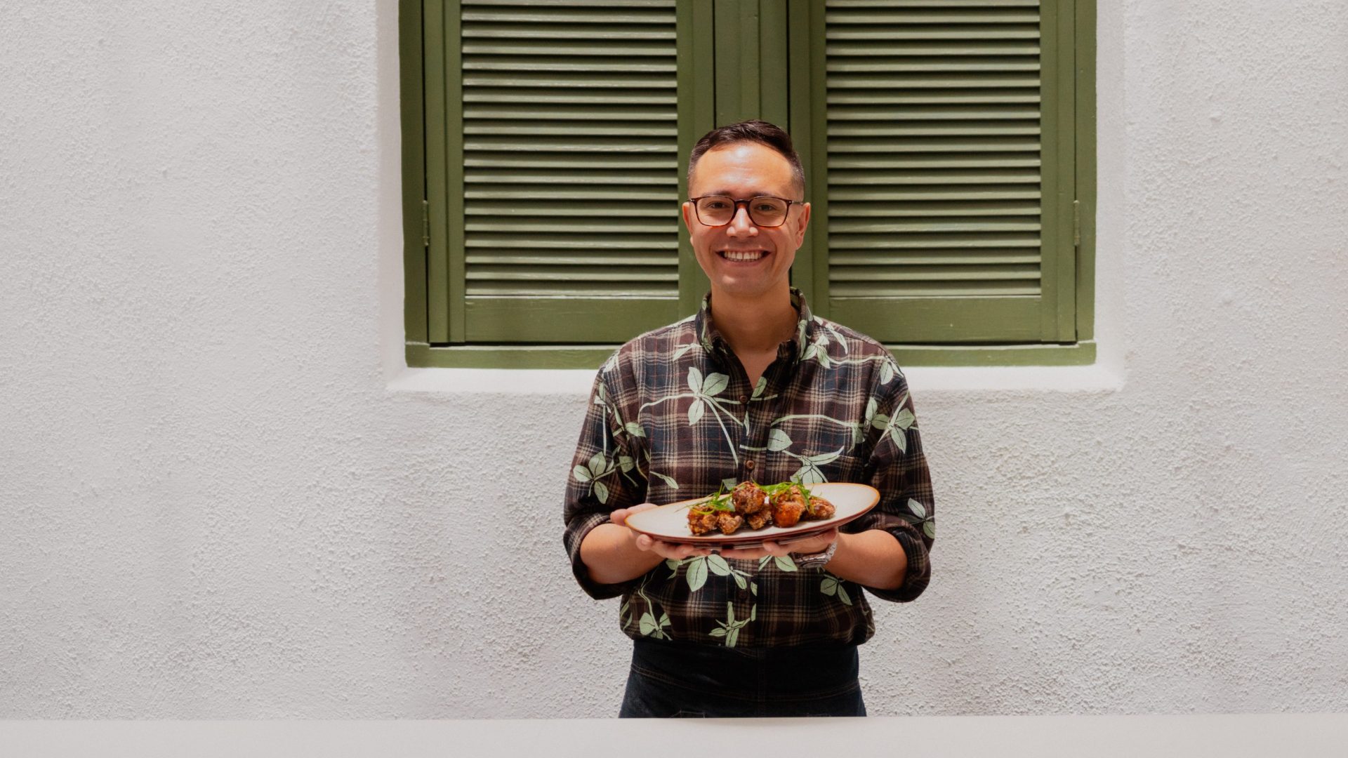 Man smiles and holds a plate of food.