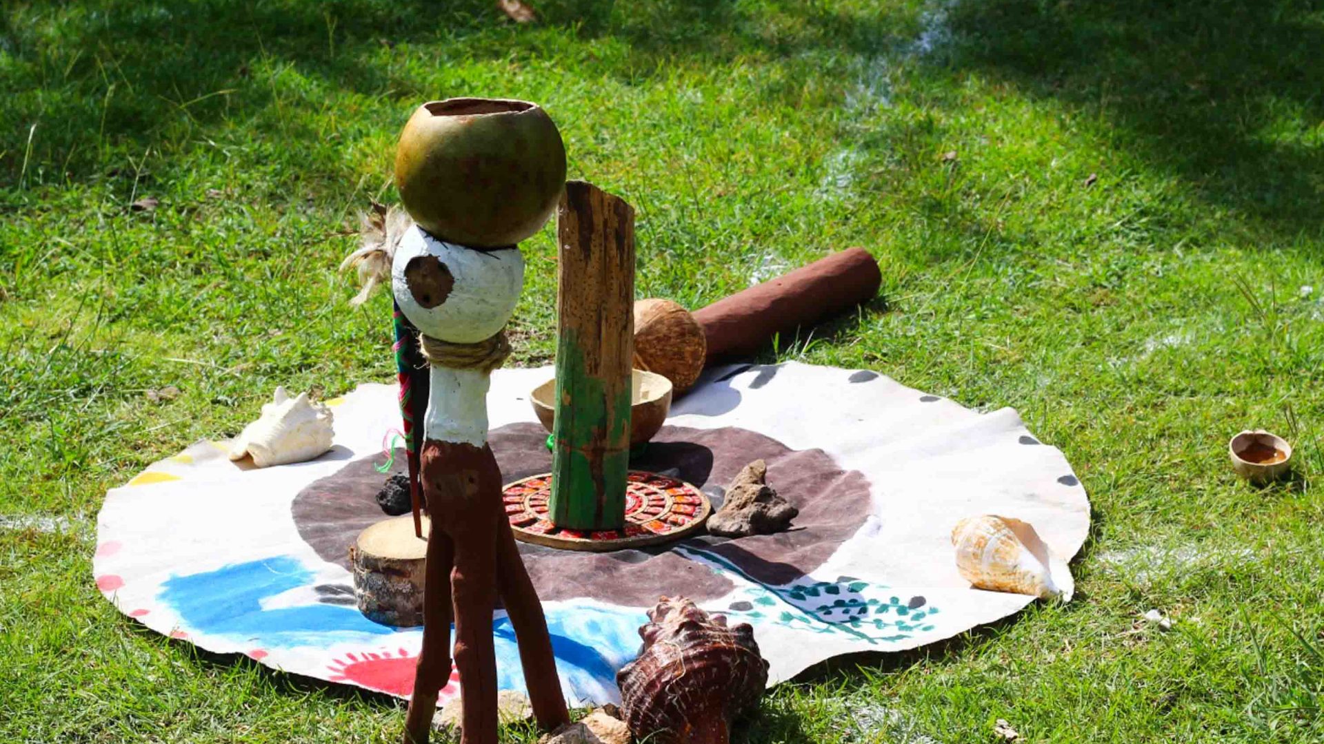 Traditional items used in a Mayan ceremony are placed on a circular mat on grass.