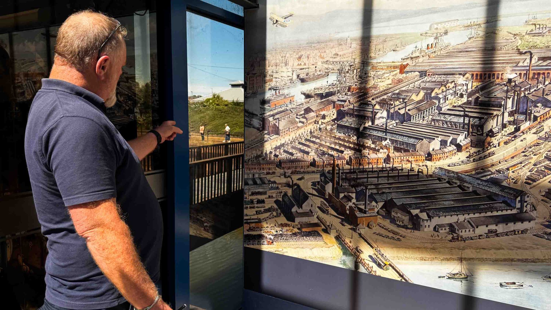 A man looks out a window at a city.