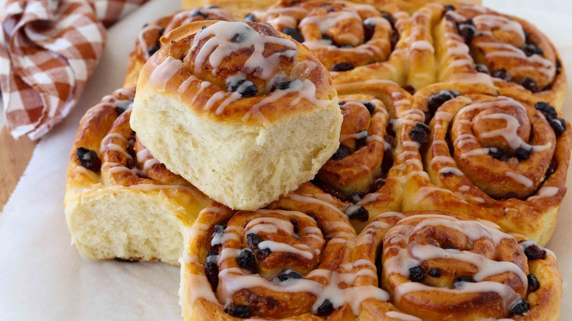A tray of buns with currents and a glaze.