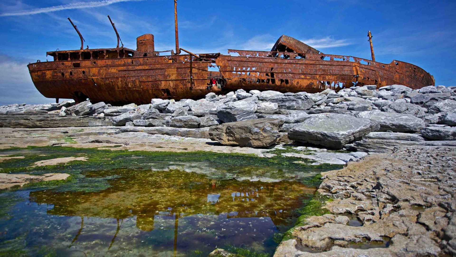 A rusting shipwreck lying on its side.