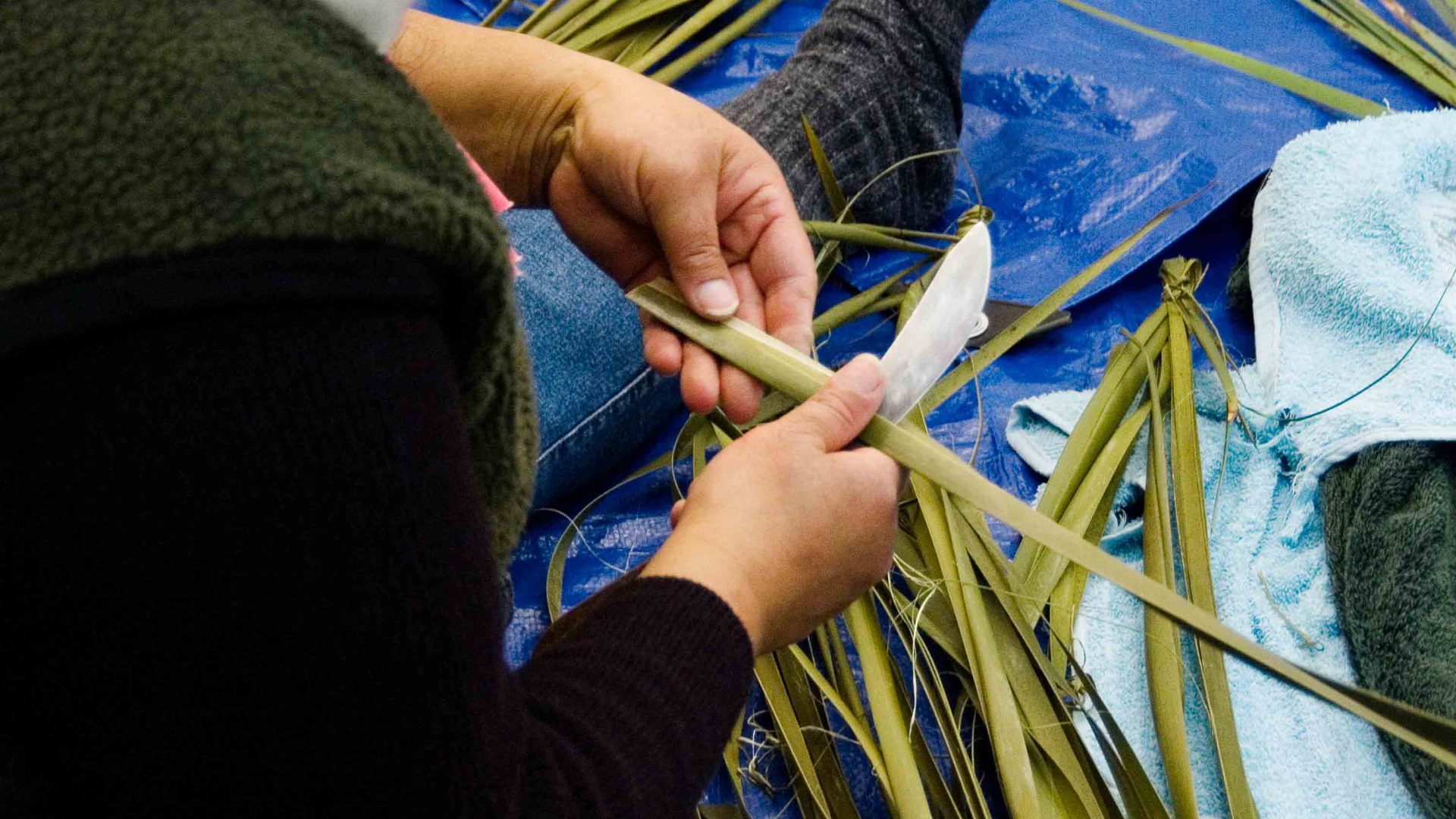 A person weaves with leaves.