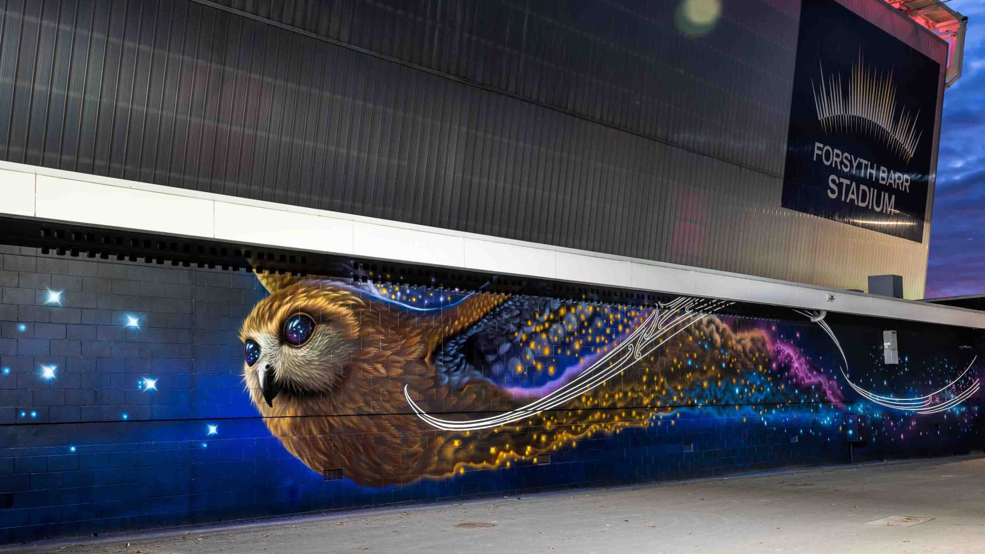 A wall mural of a bird flying toward stars.