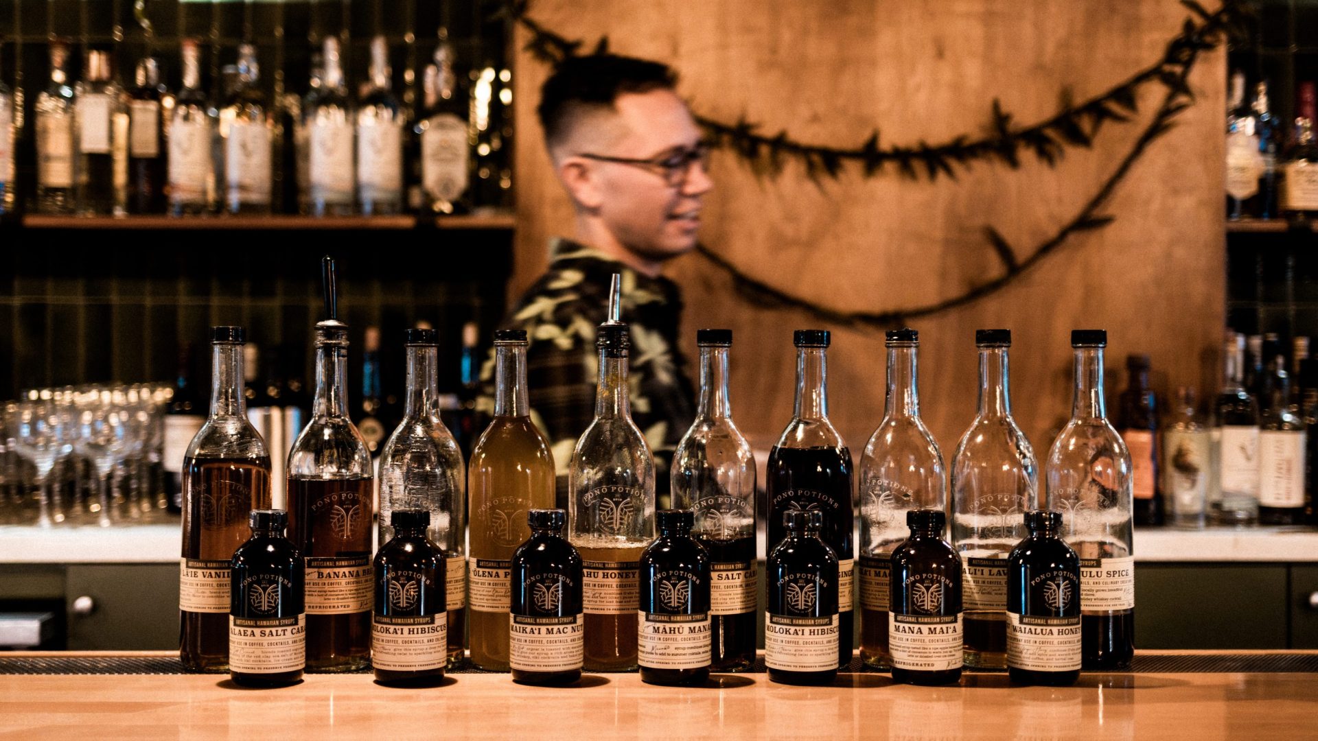 A collection of syrup bottles lined up on bar counter top.