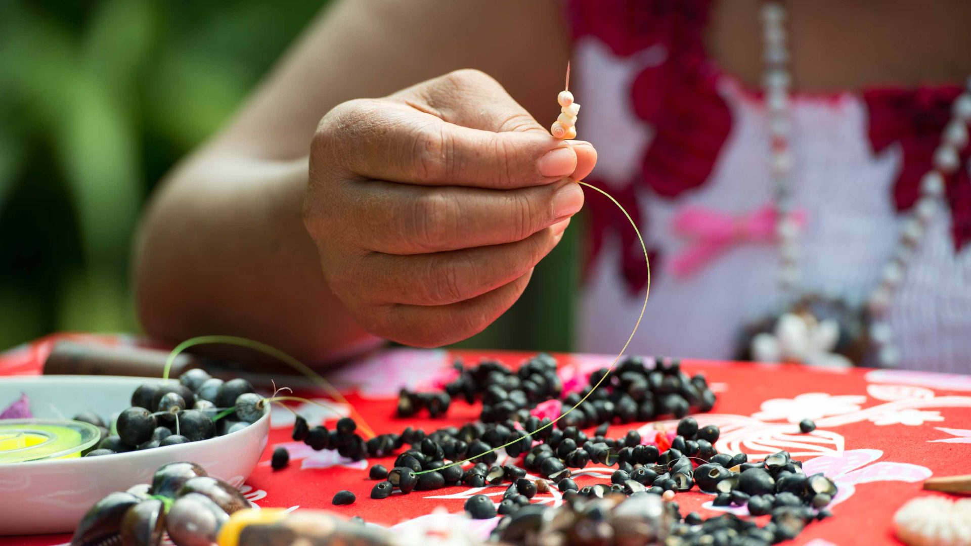 A woman sews with seeds to make jewellery.