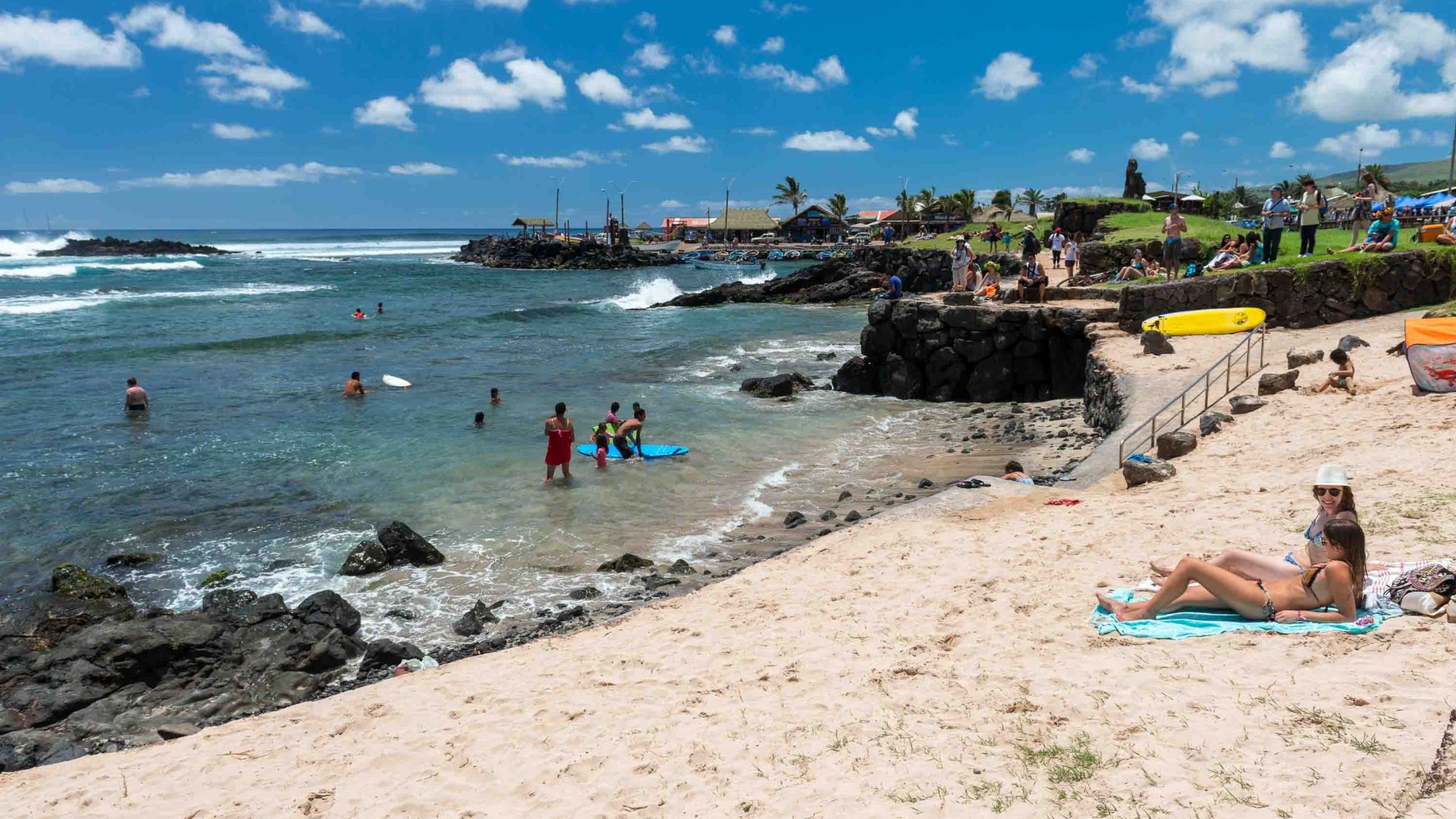 People at a beach, on the sand and in the water.