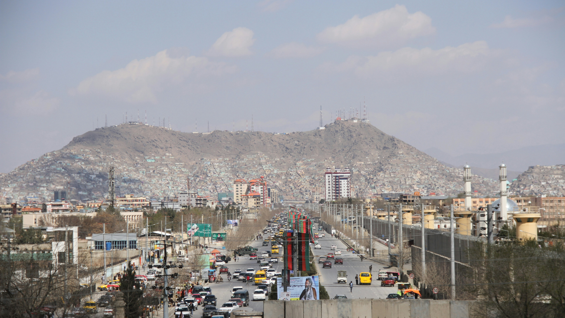 Grey city beneath mountain and dusky sky.