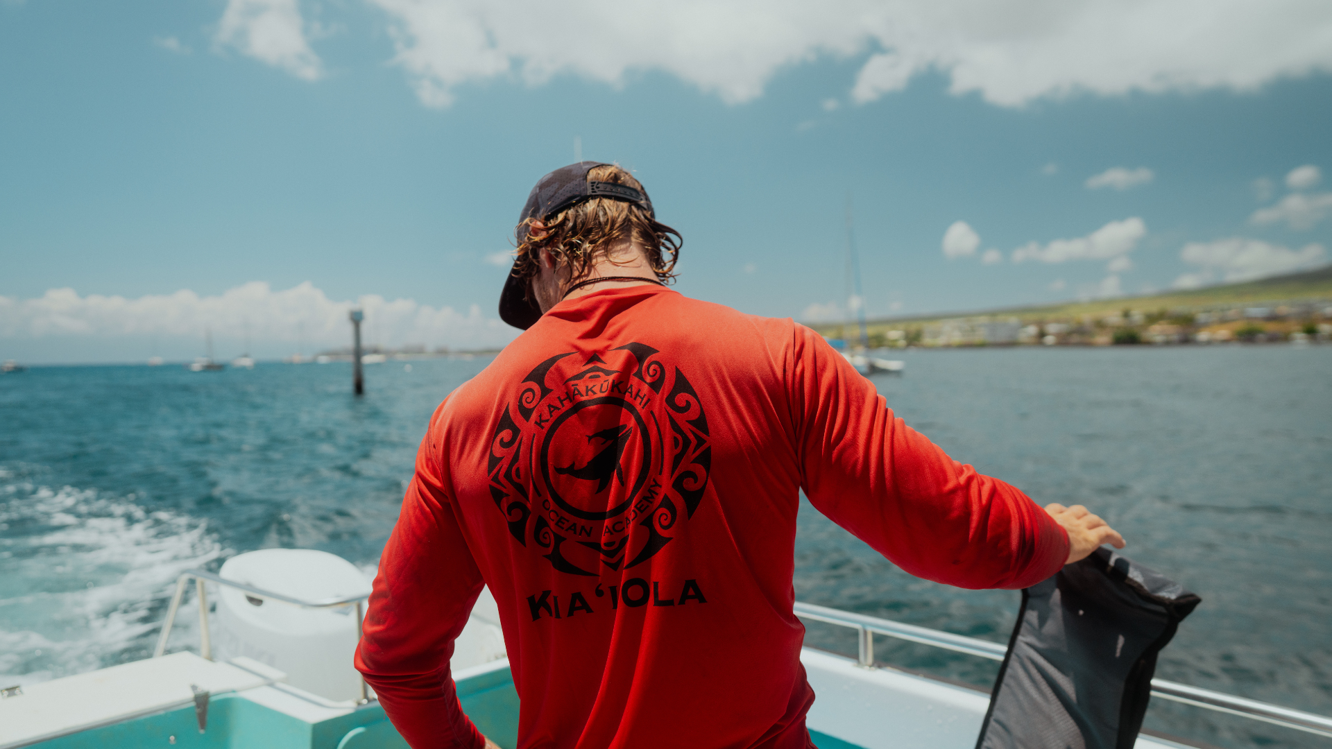 Man wears red shirt reading 'Kahākūkahi Ocean Academy'.