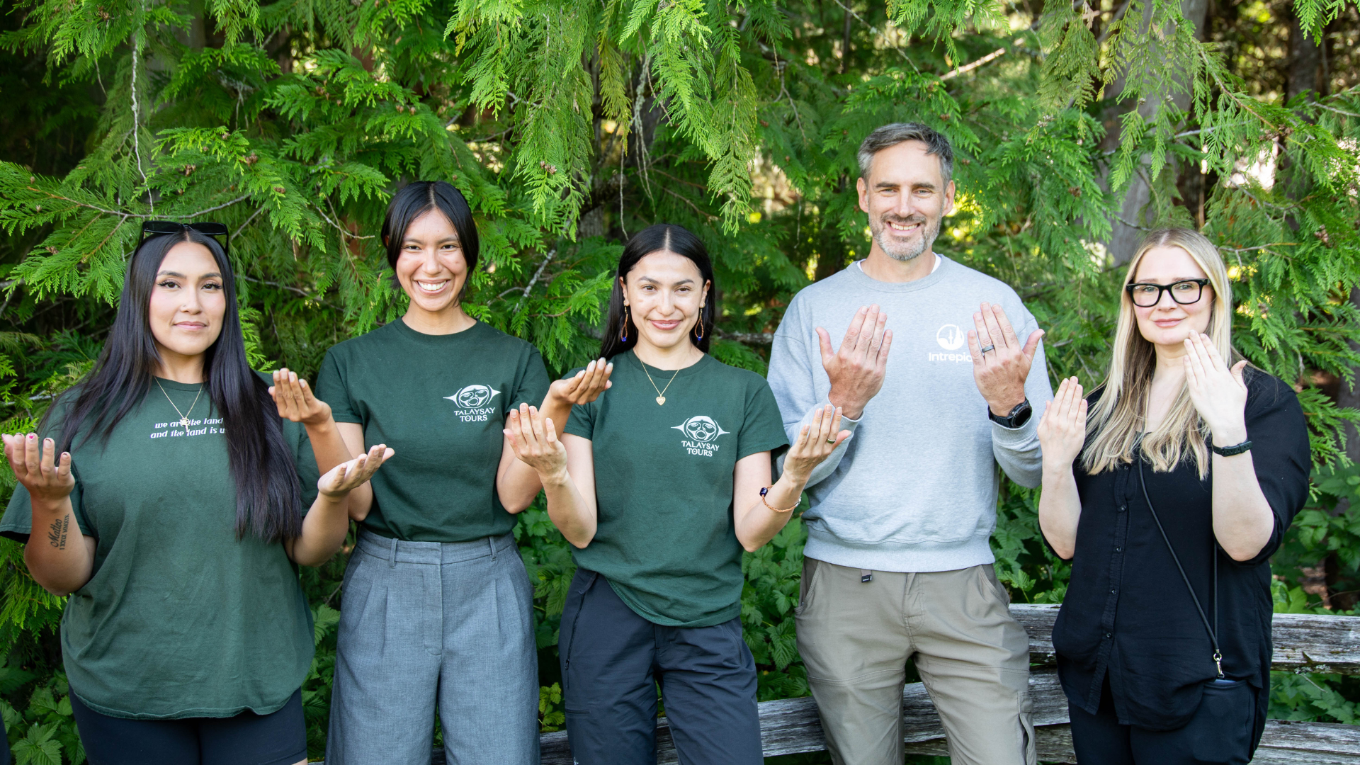 Five people pose for photo smiling and hands raised