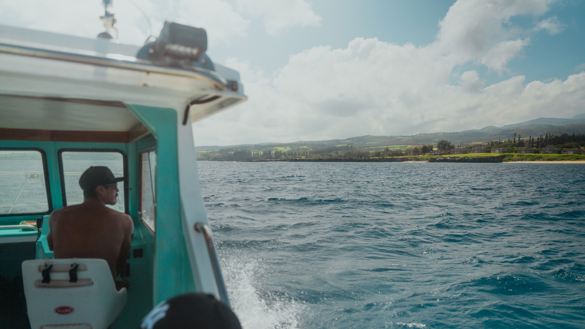 Man drives light blue boat across water.