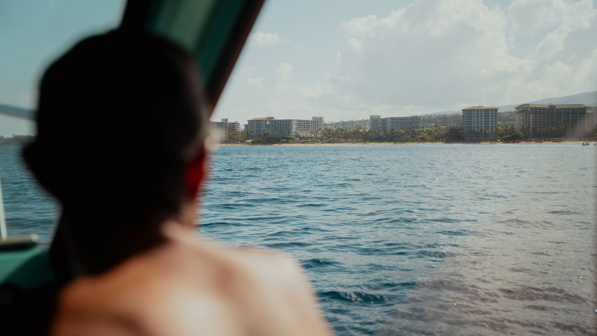 View over man's shoulder to west Maui coastline.