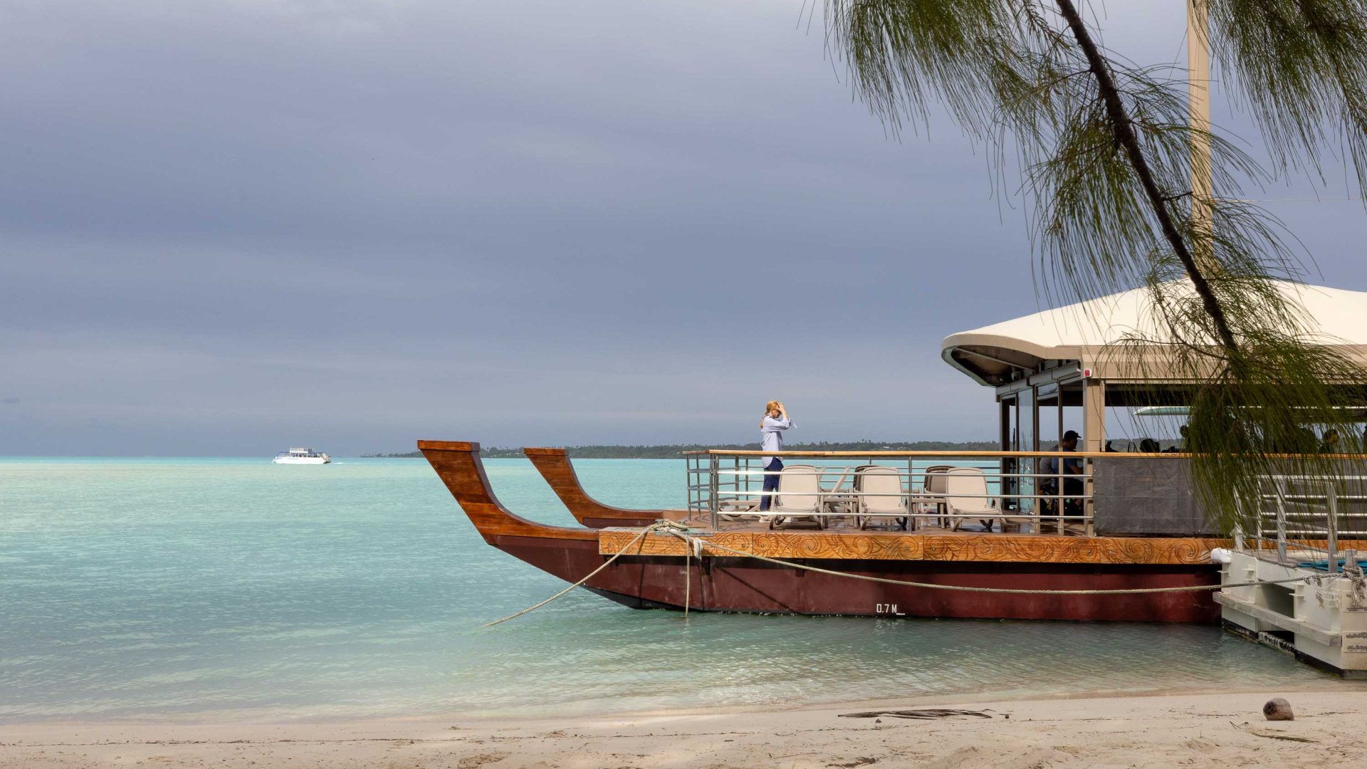A wooden boat docks in a blue lagoon.