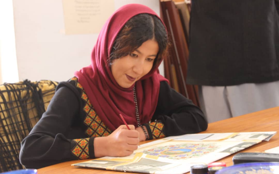 Woman wearing red scarf writes in book.