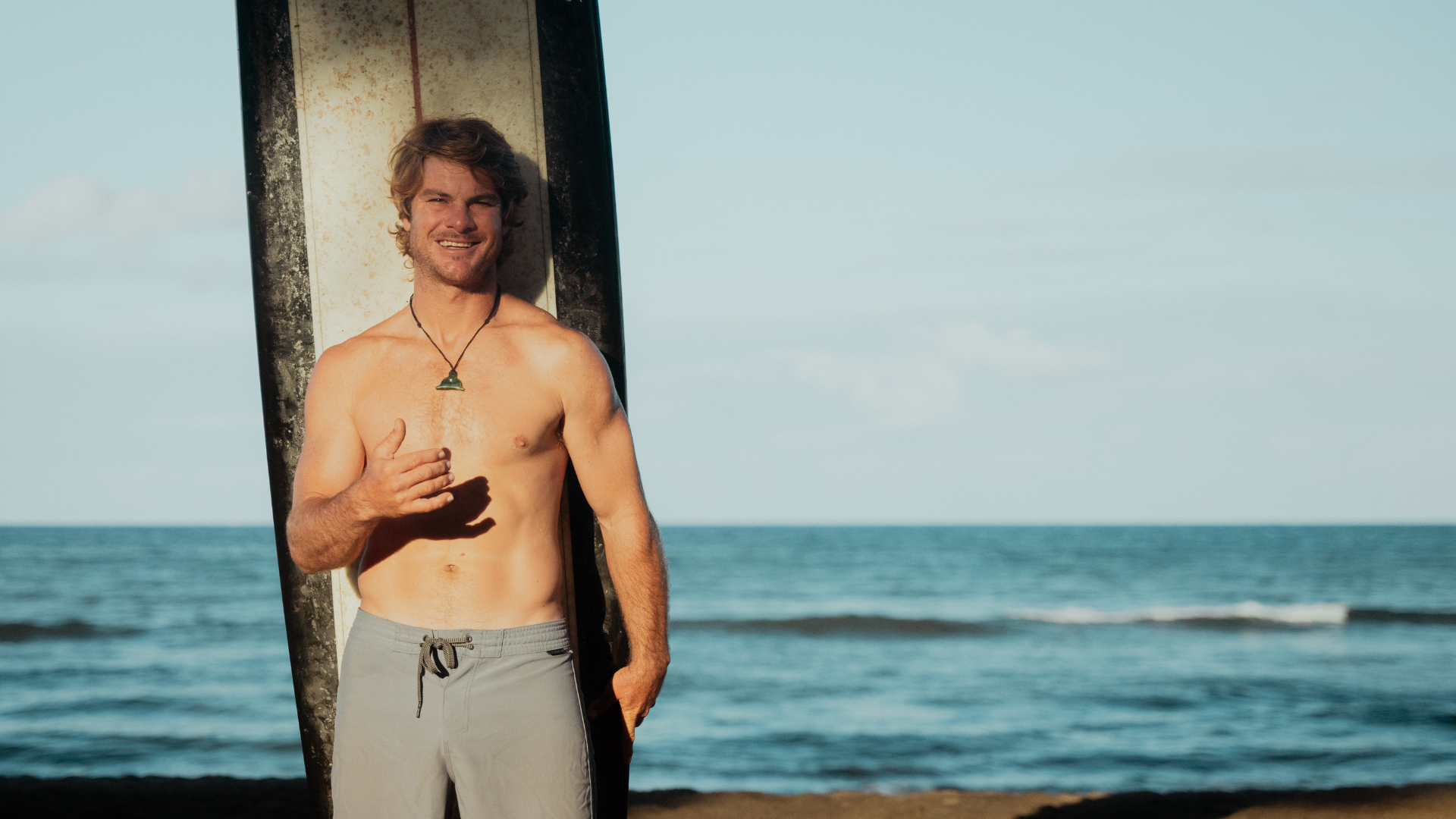 Man holding surfboard smiles