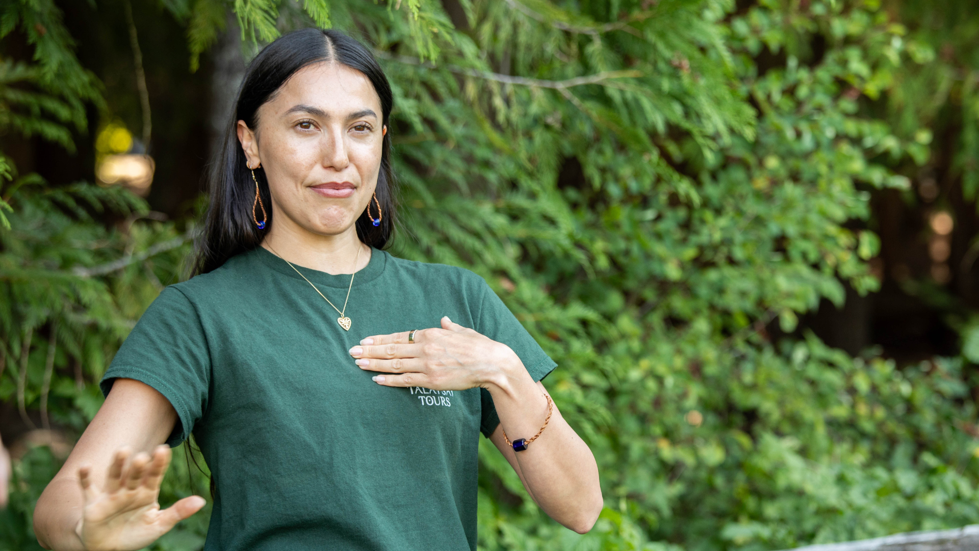 Woman wearing green shirt points to chest