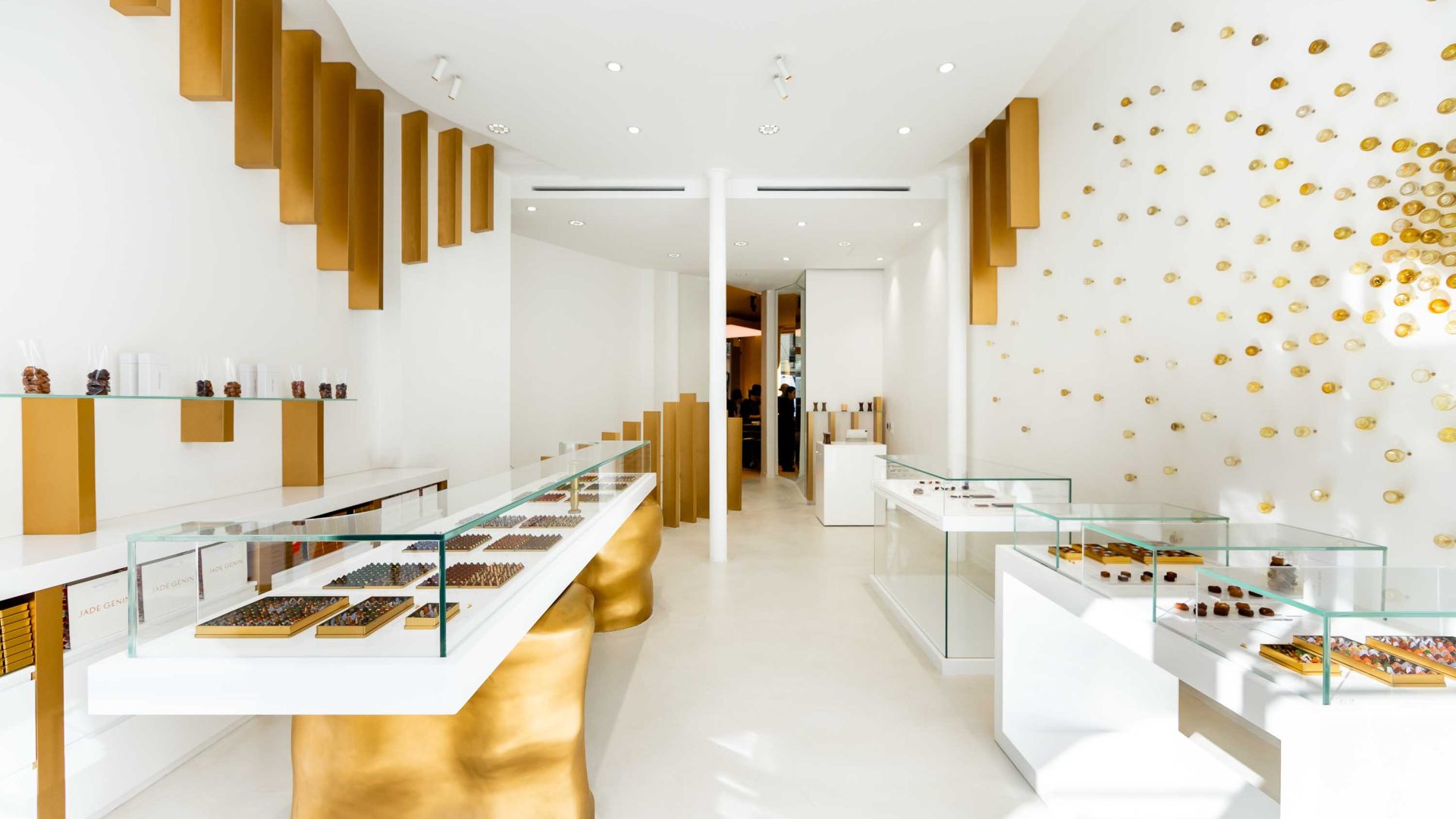 The interior of a chocolate shop with gold trimmings and white walls.