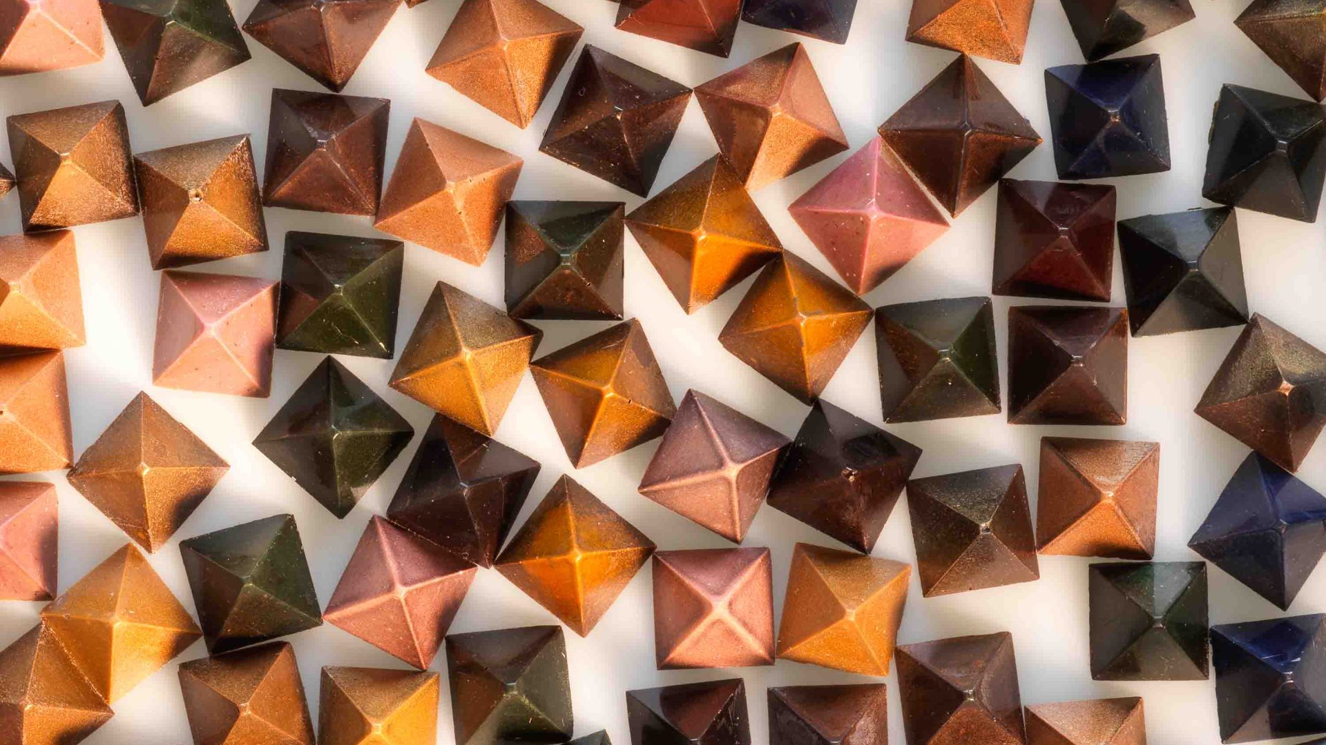 An array of different brown coloured pyramid shaped chocolates.