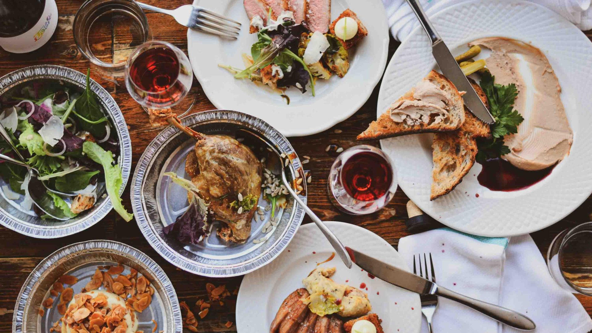 A table laid out with traditional French food including duck, foie gras and wine.